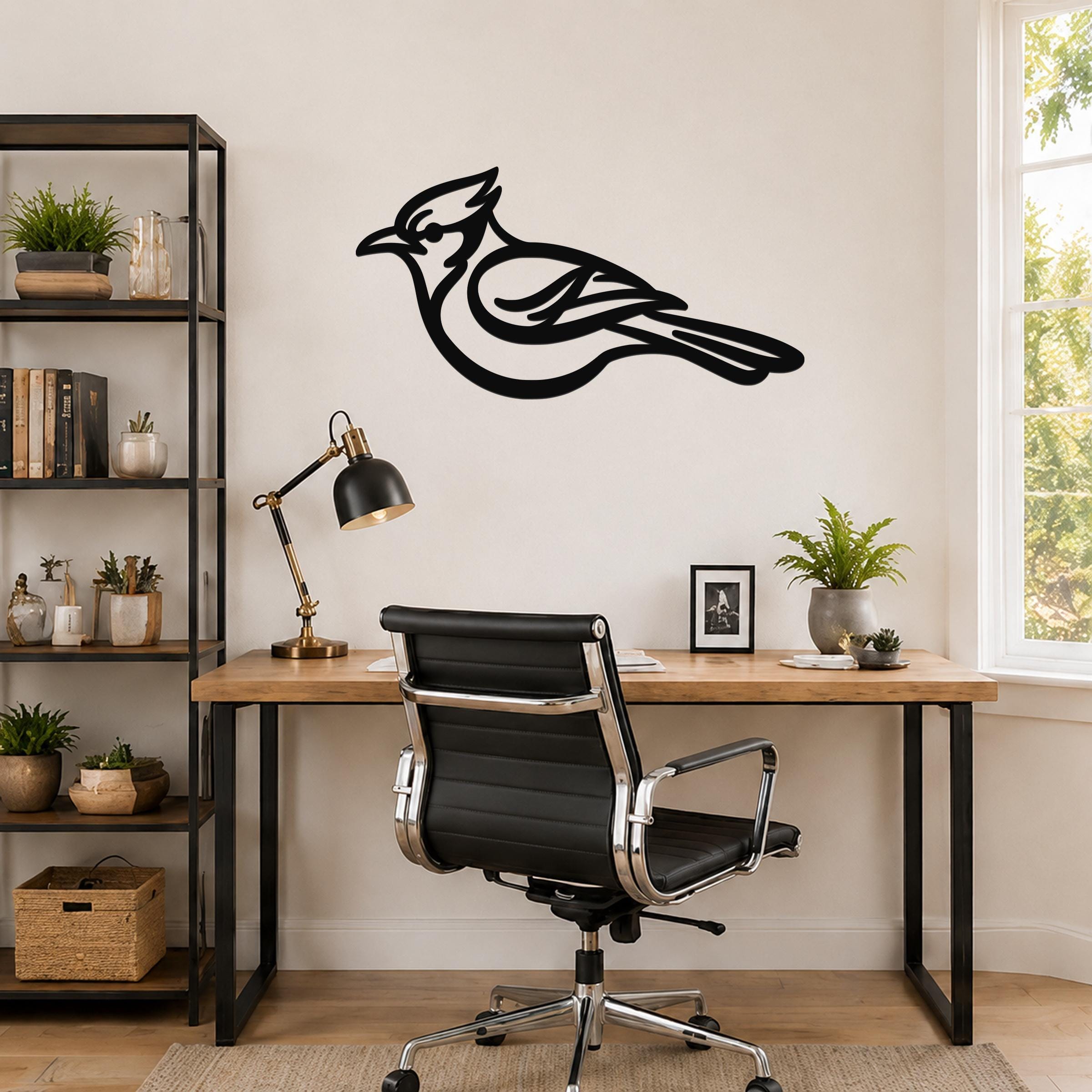 Black metal blue jay wall art silhouette mounted on a wall above a wooden desk in a home office.