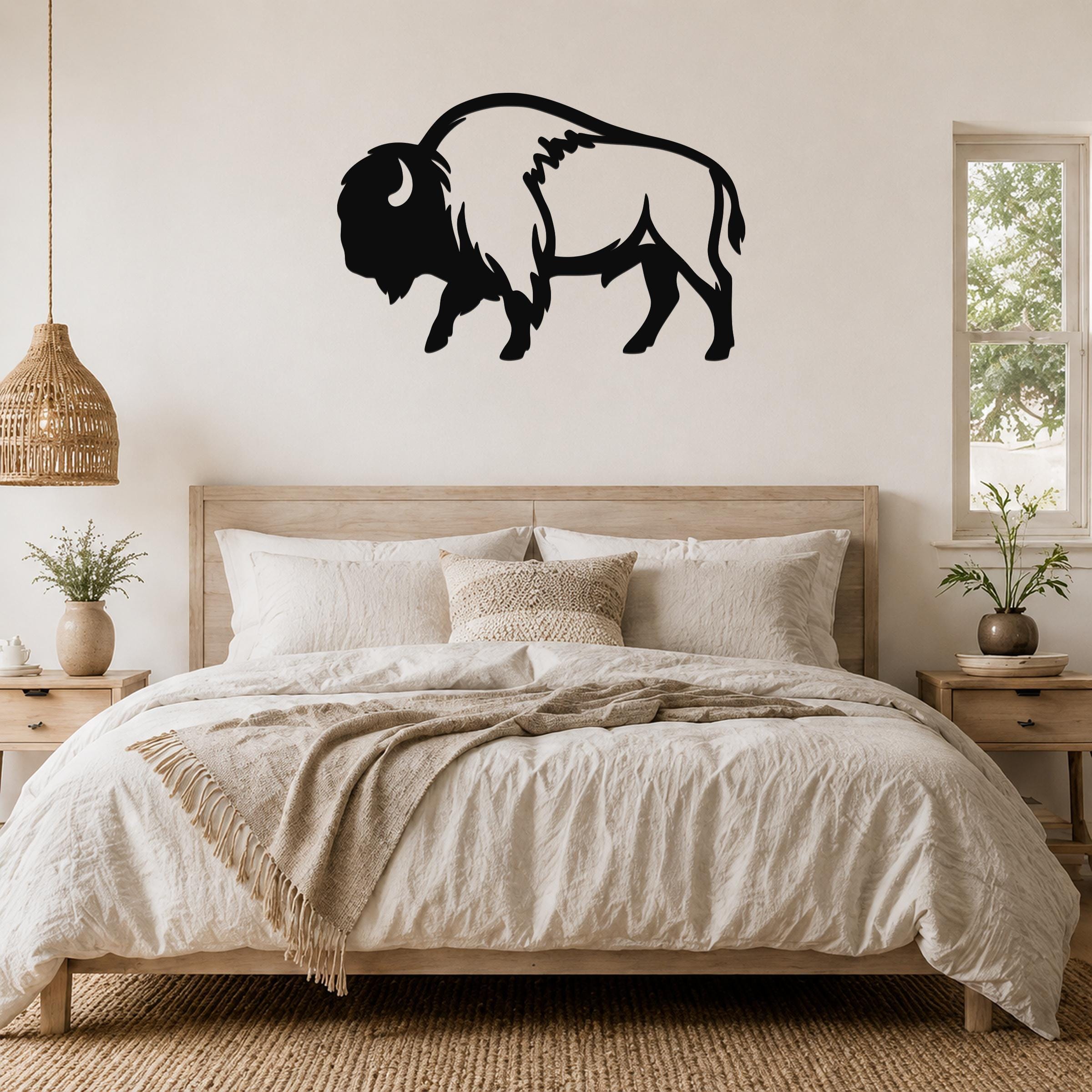 Black metal buffalo wall art silhouette mounted above a bed in a neutral bedroom.
