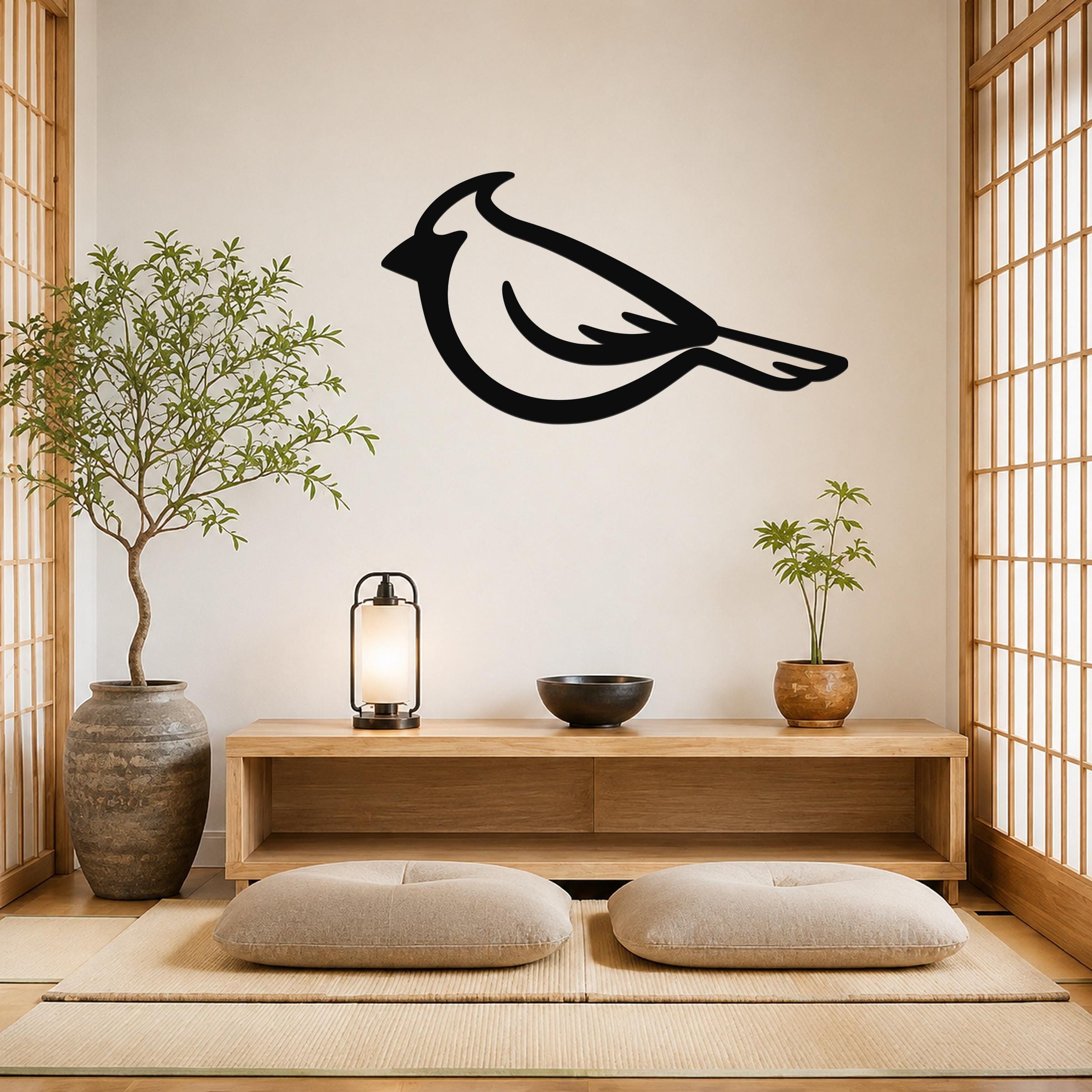 Black metal cardinal wall art silhouette mounted on a light-colored wall above a wooden console in a minimalist room with tatami mats and shoji screens.