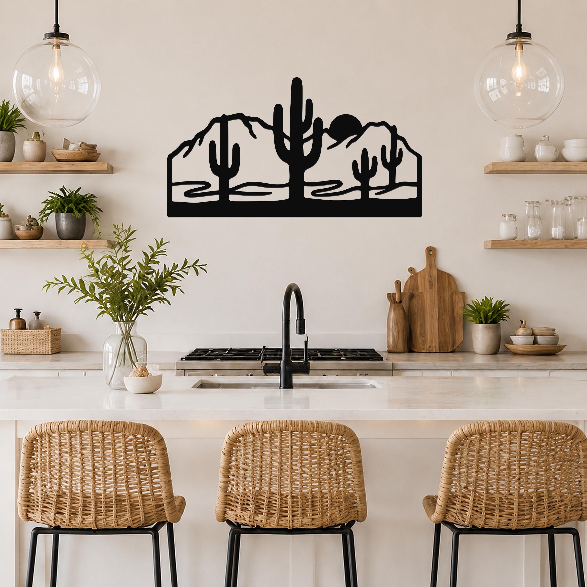 Black metal wall art with a desert silhouette of saguaro cacti and mountains, mounted above a kitchen counter.