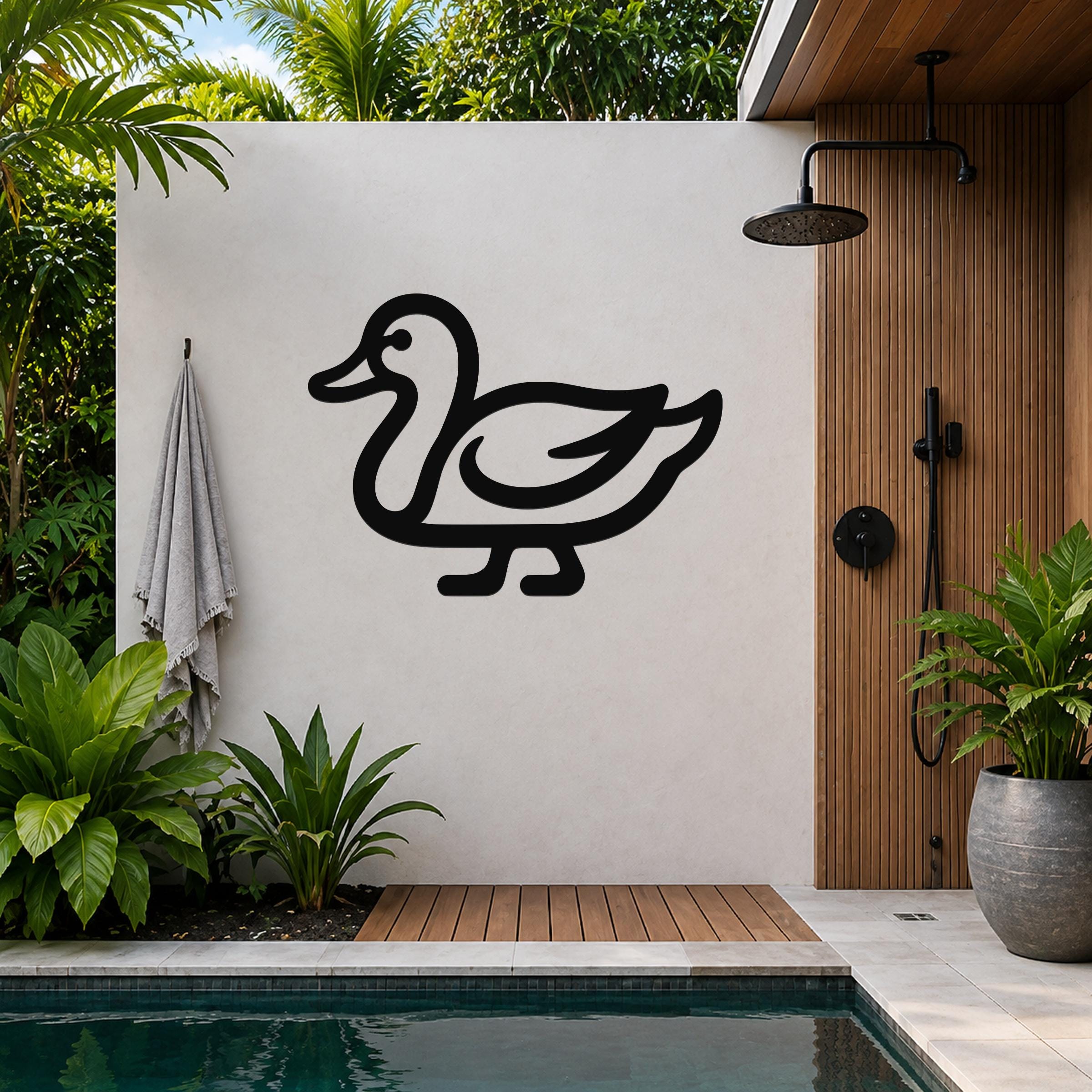 Black metal duck wall art silhouette mounted on a light-colored outdoor wall beside a wooden shower enclosure and pool.