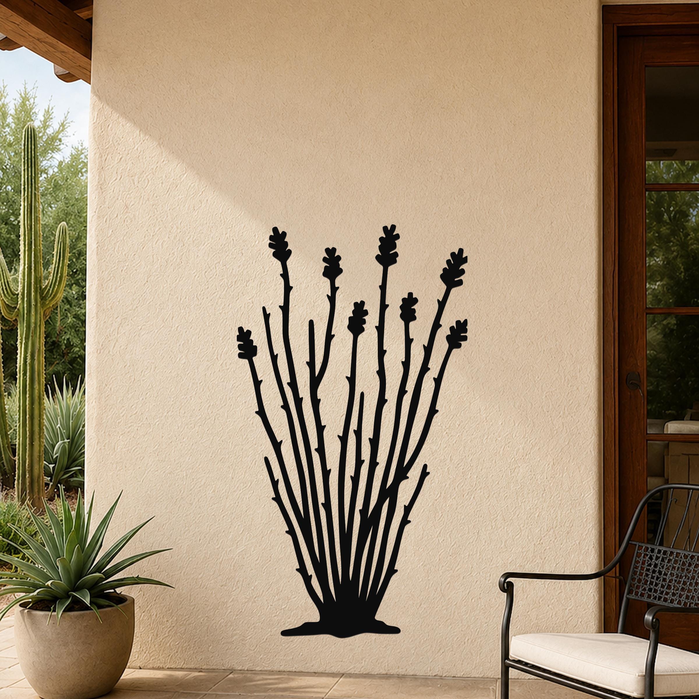Black metal ocotillo wall art with branching stems and flower cutouts, mounted on a beige outdoor wall beside a potted plant and patio chair.