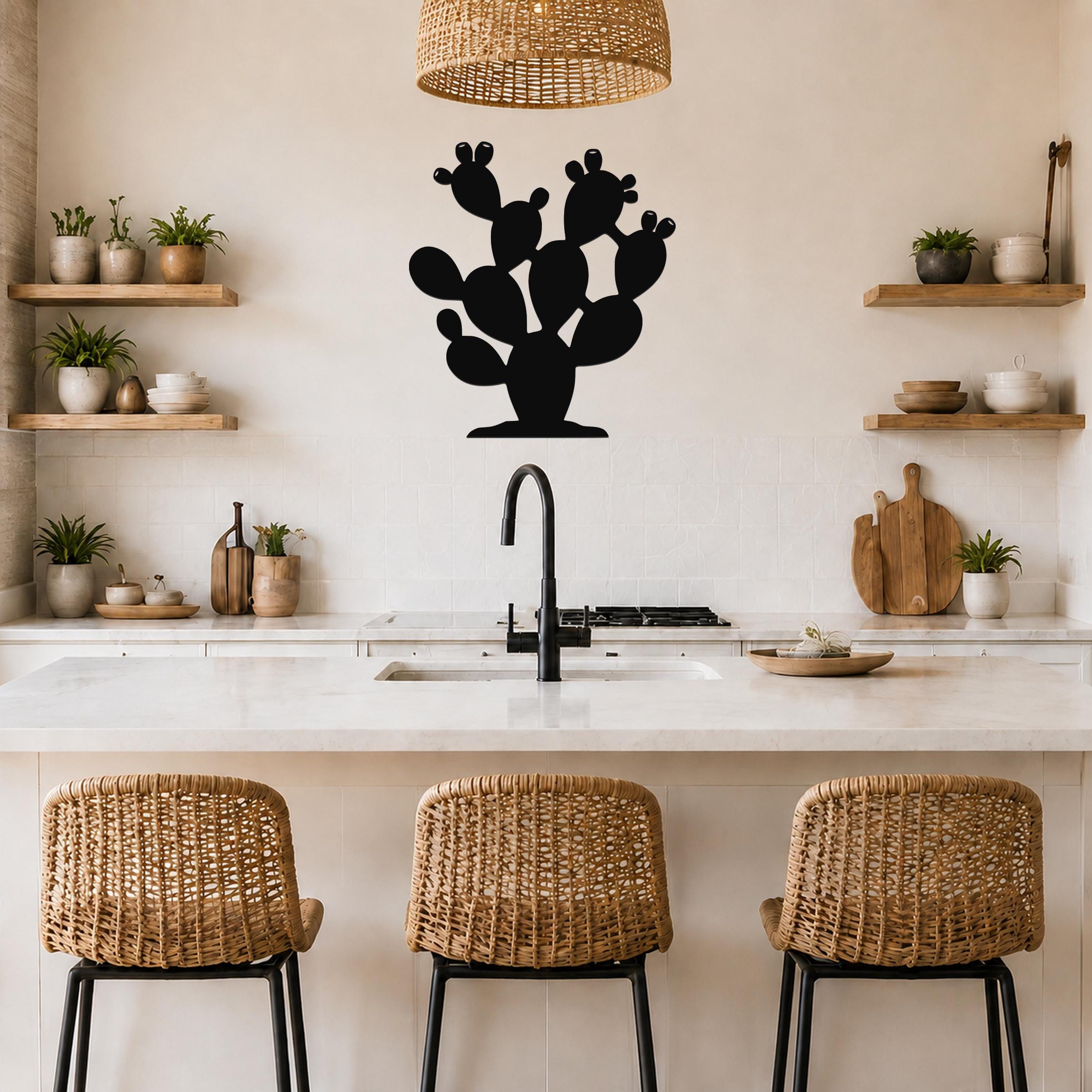 Black metal prickly pear cactus wall art with multiple pads and cutout details, mounted on a kitchen wall above a counter.
