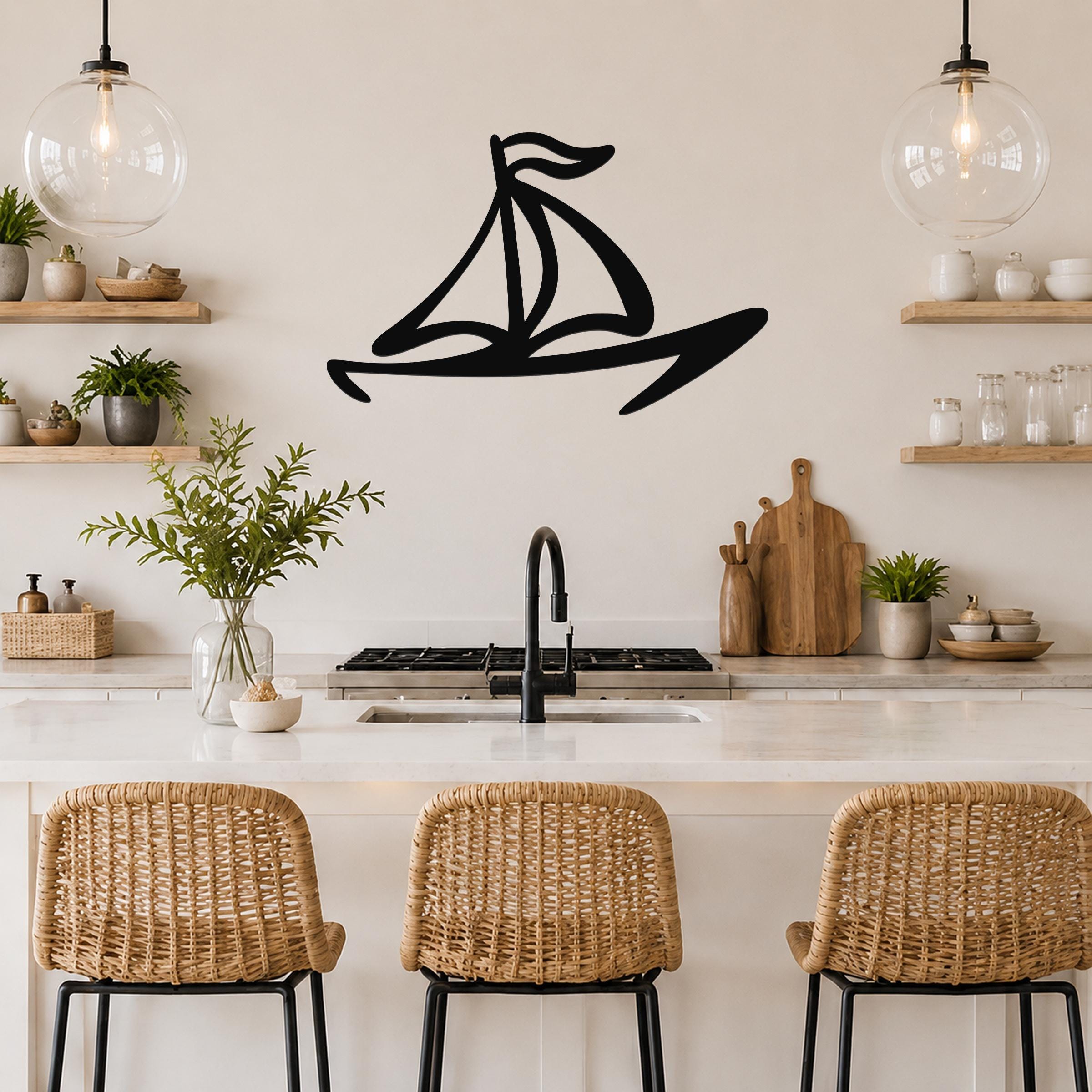 Black metal sailboat wall art with bold silhouette lines, mounted on a kitchen wall above a counter.