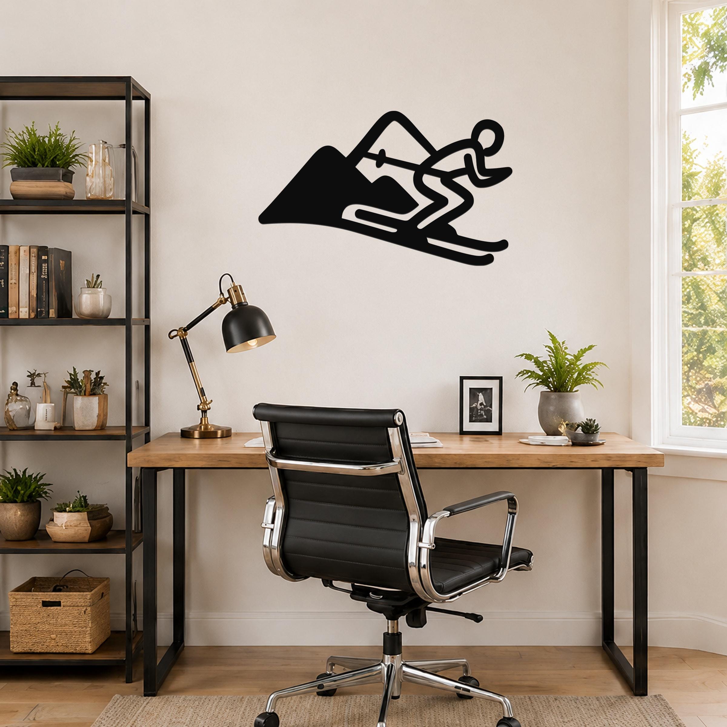Black metal skier and mountain wall art silhouette with motion lines, mounted above a wooden desk in a home office.