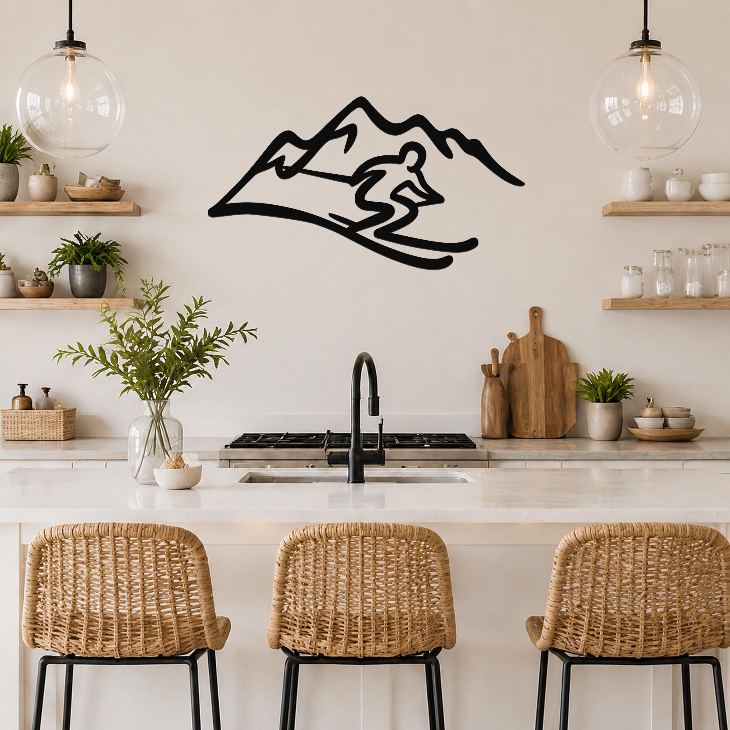 Black metal wall art featuring a skier silhouette in motion against a mountain range, mounted on a kitchen wall above a counter.