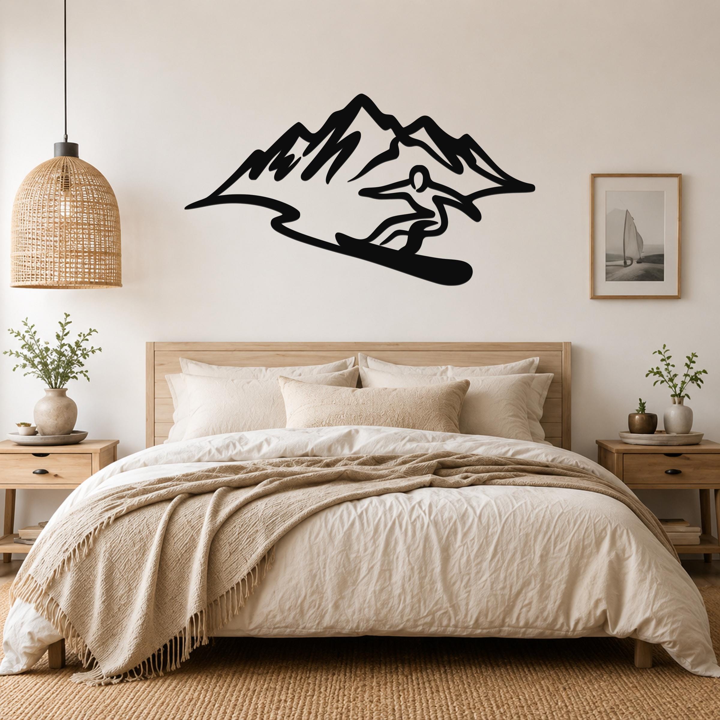 Black metal wall sculpture of a snowboarder in silhouette, mounted above a bed in a bedroom.