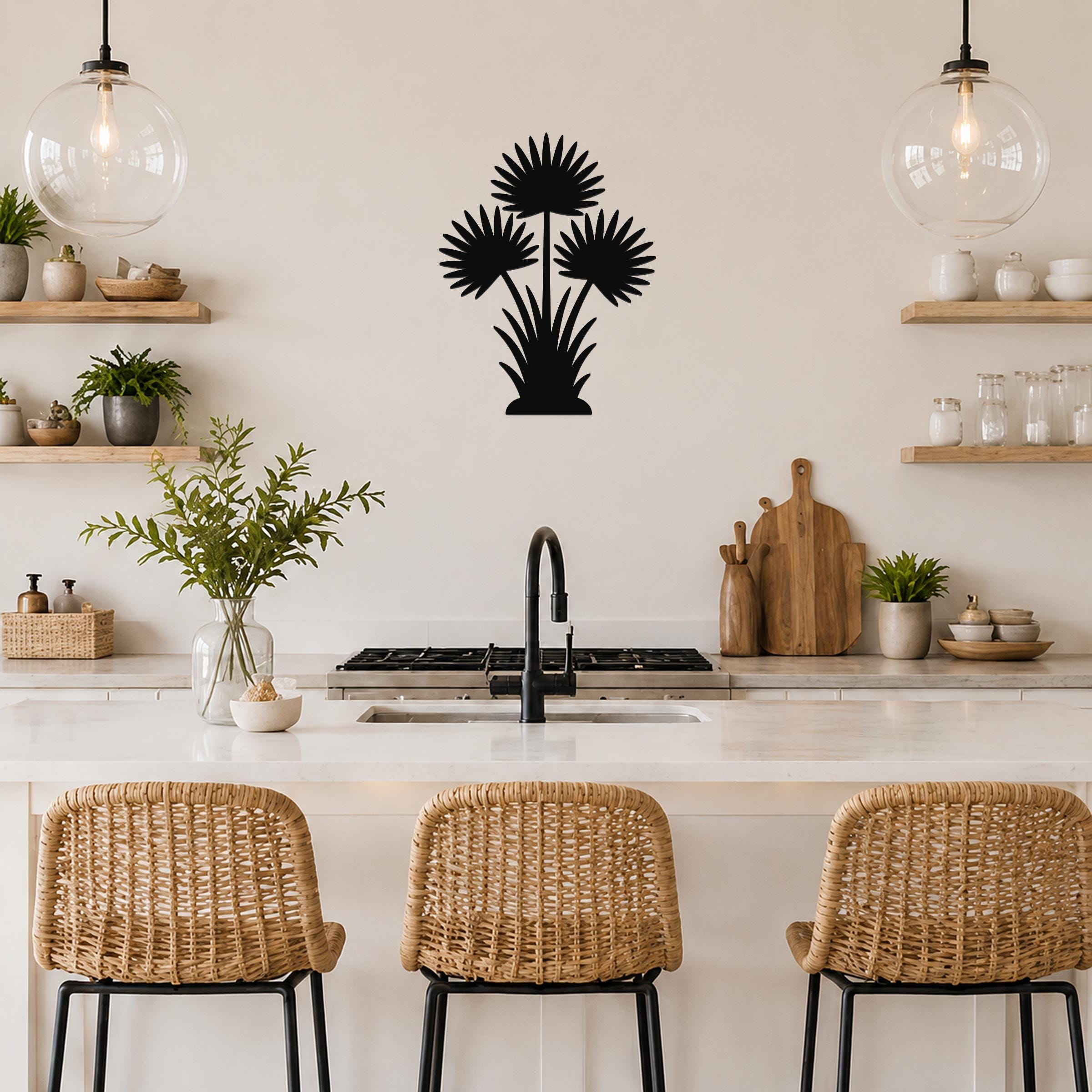 Black metal fan palm tree wall art with three flower cutouts and leafy base, mounted on a kitchen wall above a counter.