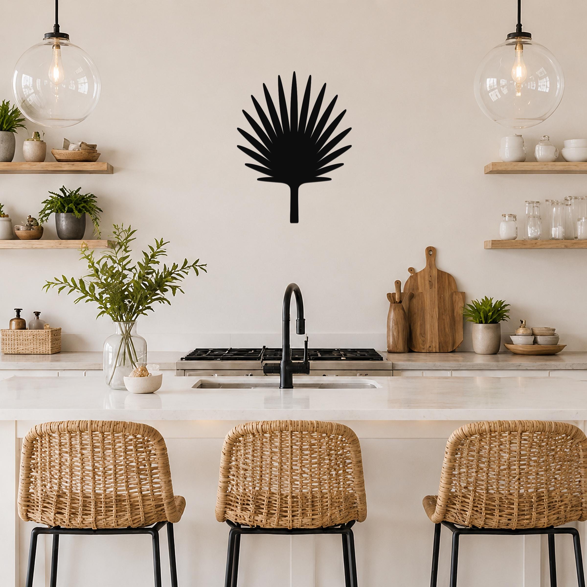 Black metal fan palm tree wall art with radiating leaf cutouts, mounted on a kitchen wall above a counter.