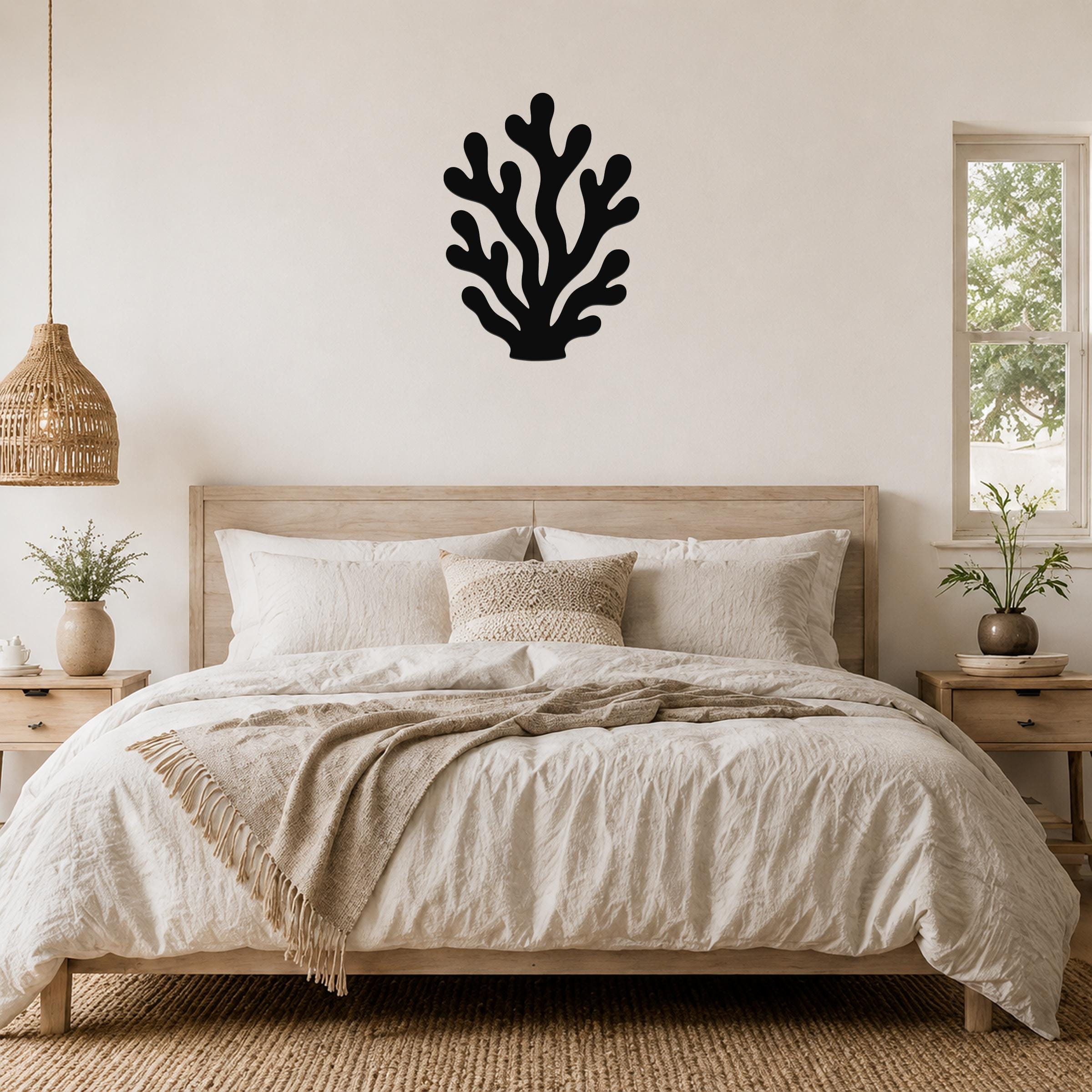 Black metal coral wall art with branching cutouts, mounted above a wooden bed in a neutral bedroom.