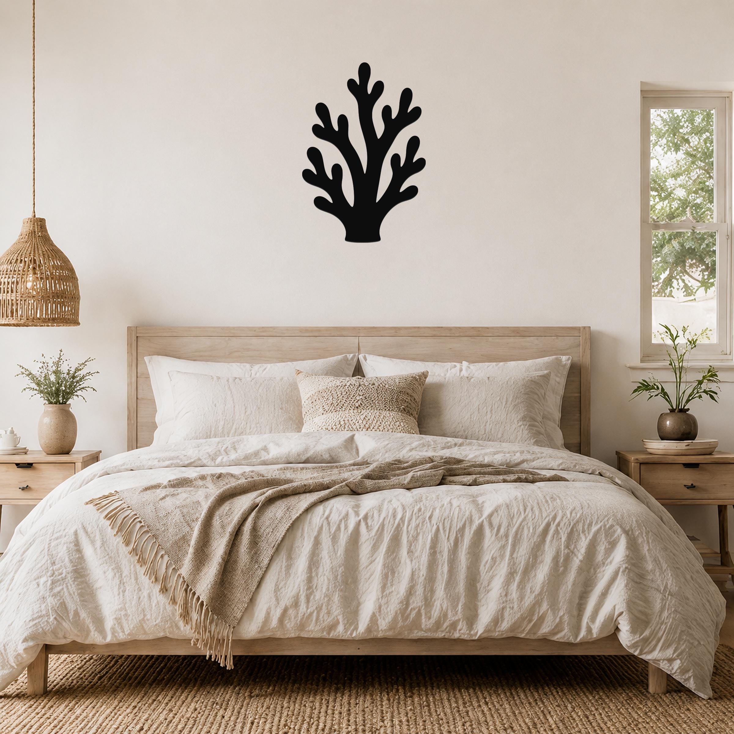 Black metal branching coral wall art with cutout details, mounted above a wooden bed in a neutral bedroom.