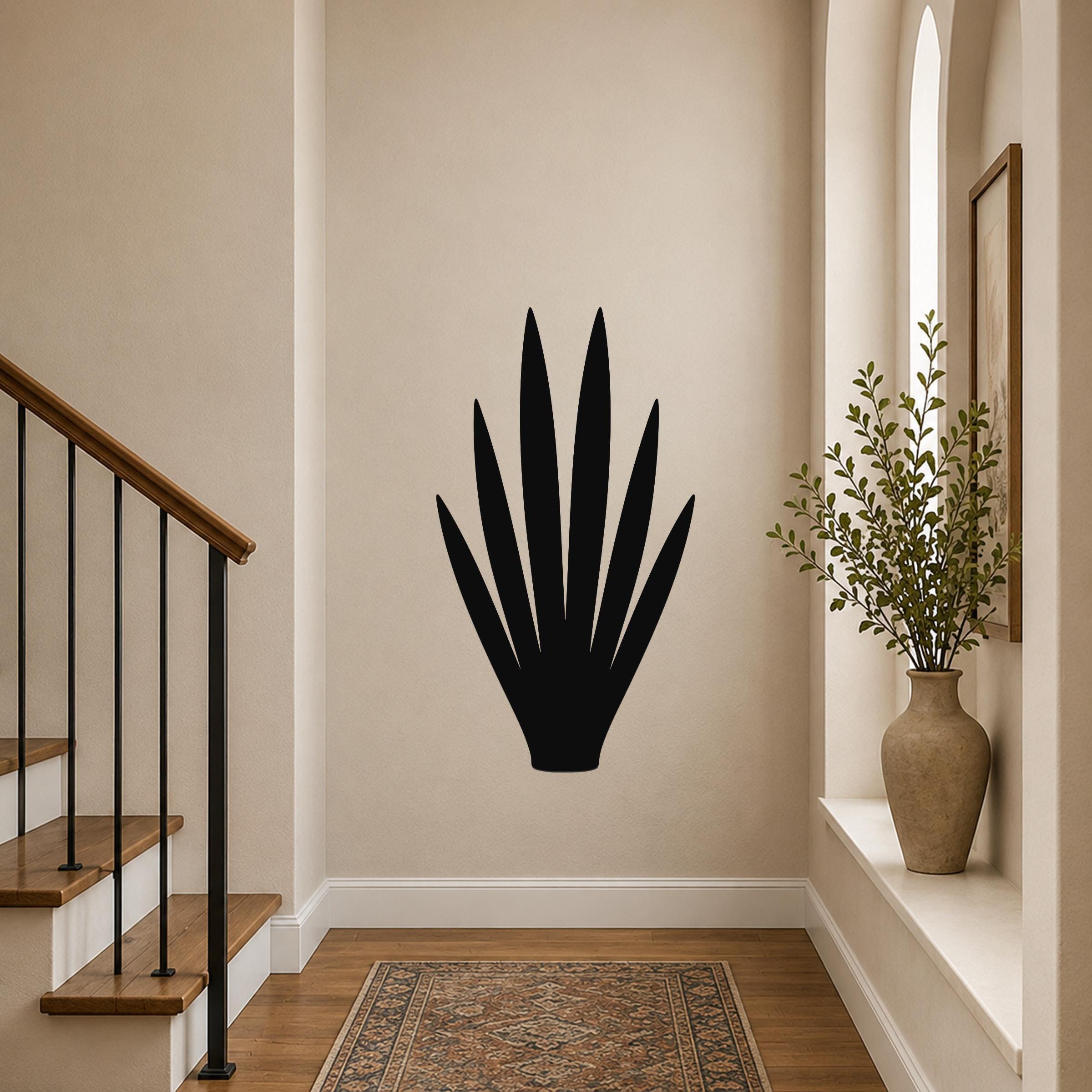 Black metal yucca wall art silhouette with spiky leaves, mounted on a beige hallway wall above a patterned rug near a staircase.