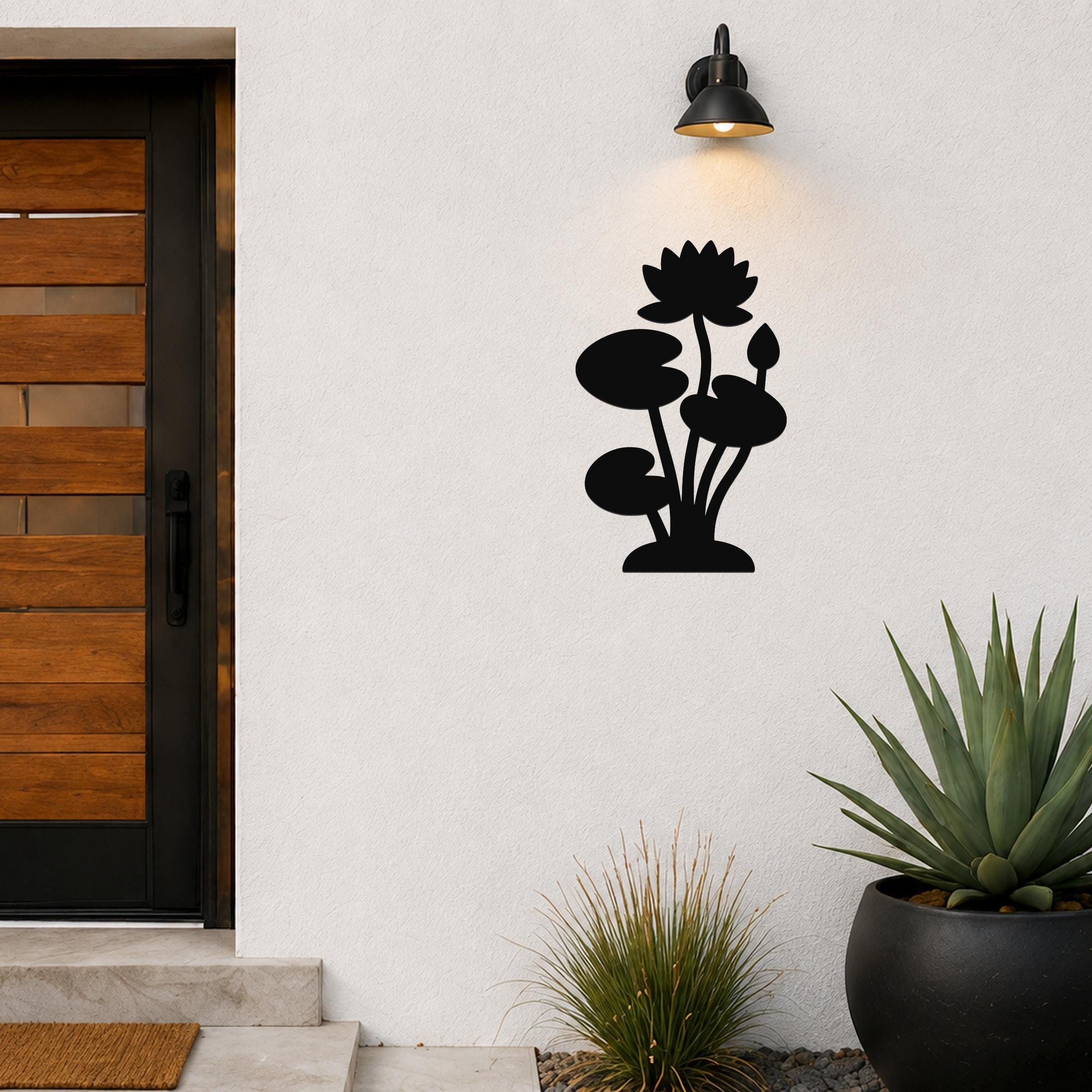 Black metal lotus water lily wall art with flower and leaf cutouts, mounted on an outdoor wall beside a front door.