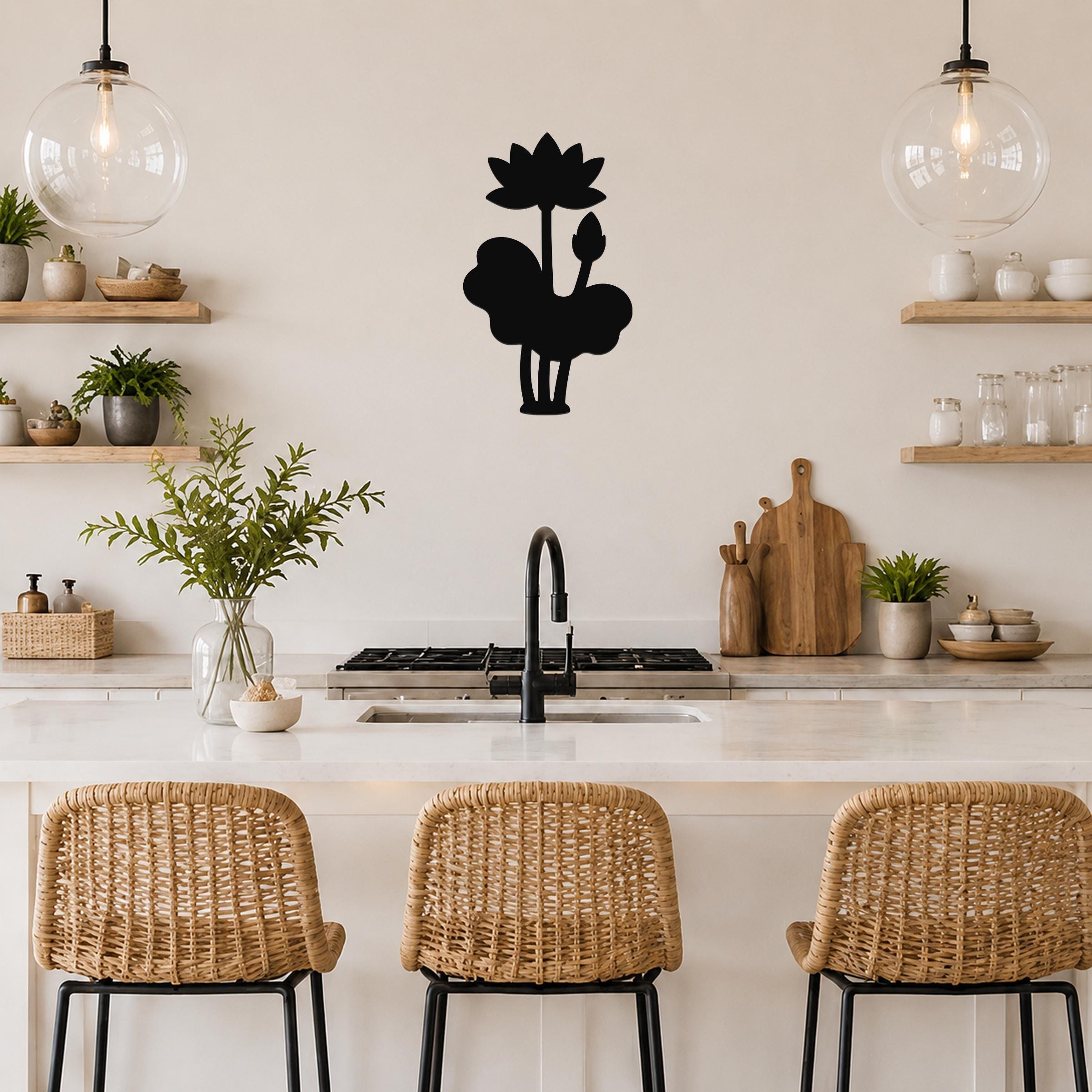Black metal lotus wall art silhouette with flower and leaf cutouts, mounted on a kitchen wall above a counter.