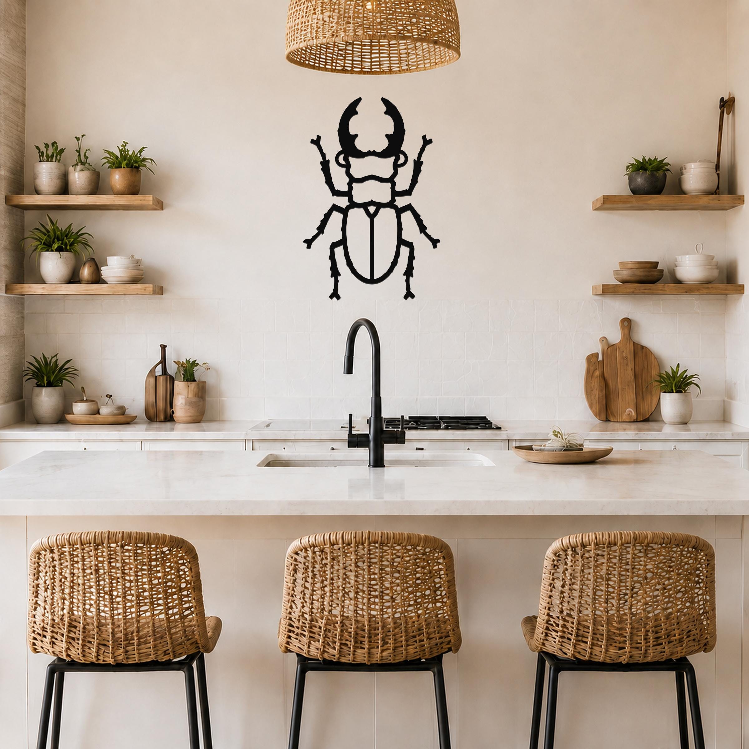 Black metal beetle wall art with detailed cutout silhouette, mounted on a kitchen wall above a marble countertop.