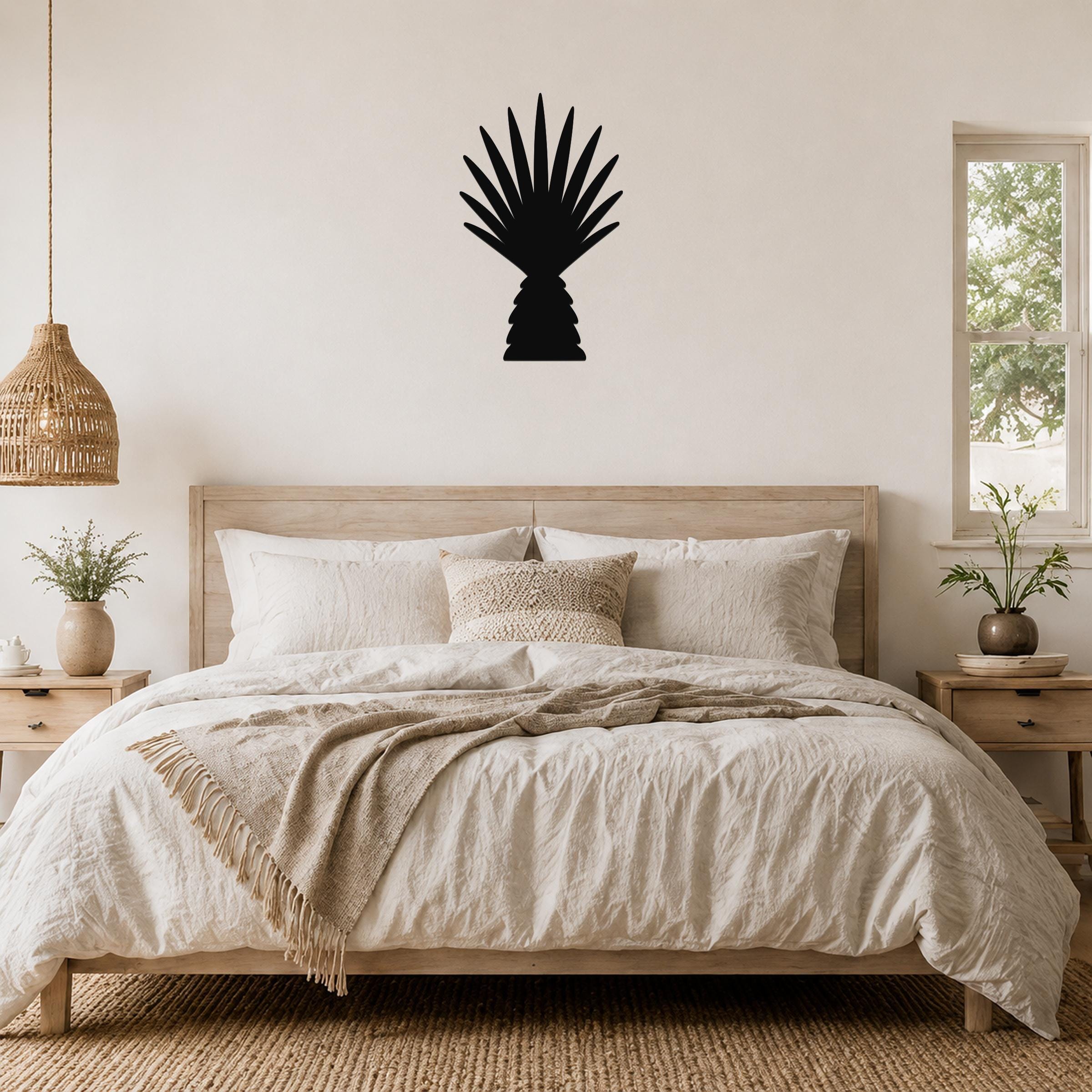 Black metal palm tree wall art with fan-shaped fronds, mounted above a wooden bed in a neutral bedroom.