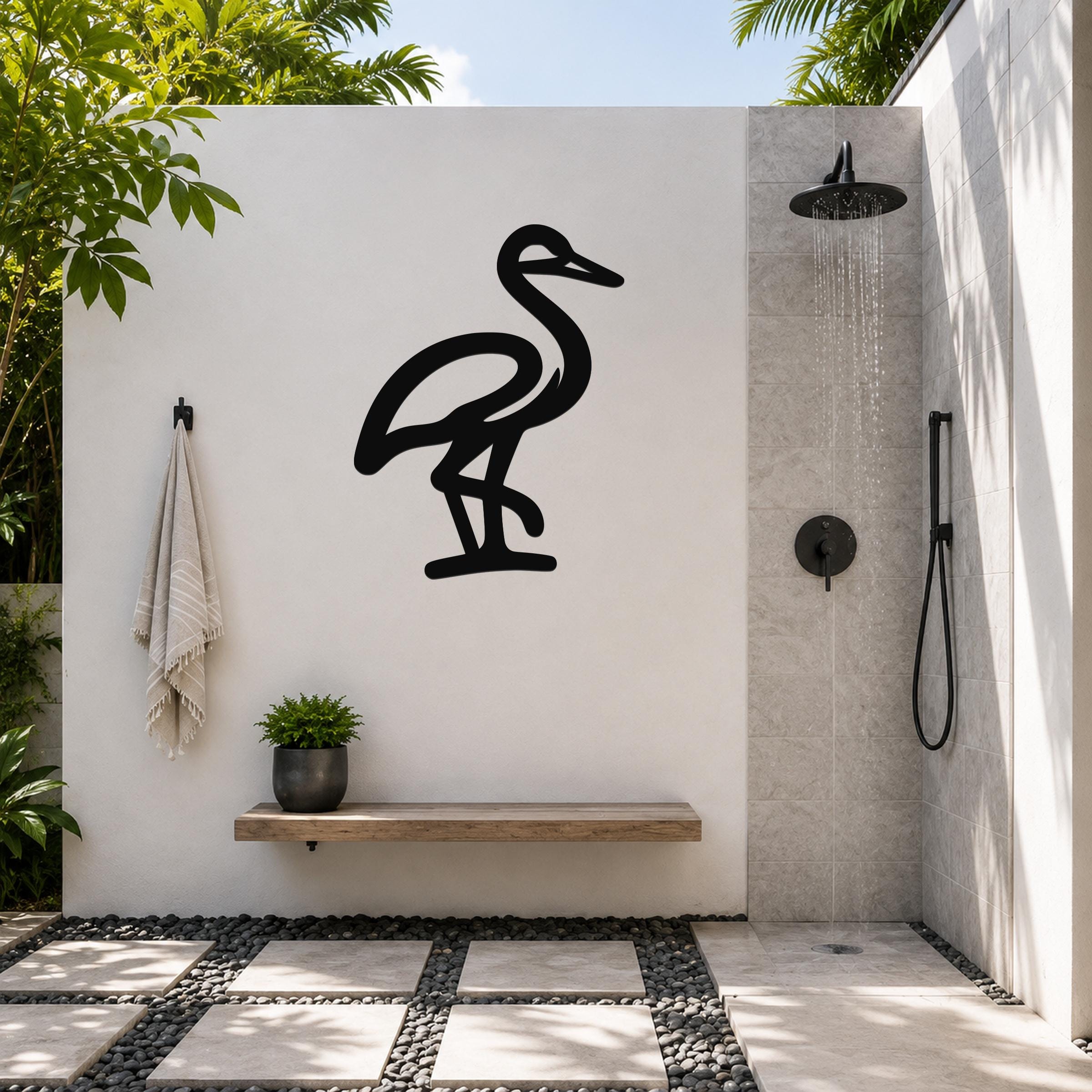Black metal crane wall art silhouette mounted on a white outdoor wall above a wooden bench in a modern shower area.