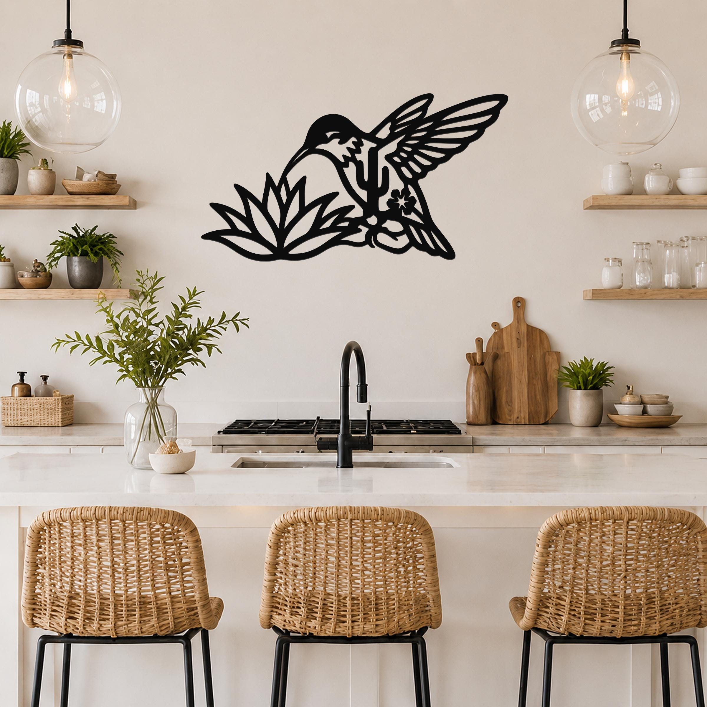 Black metal hummingbird wall art with cactus and flower cutouts, mounted above a kitchen counter.