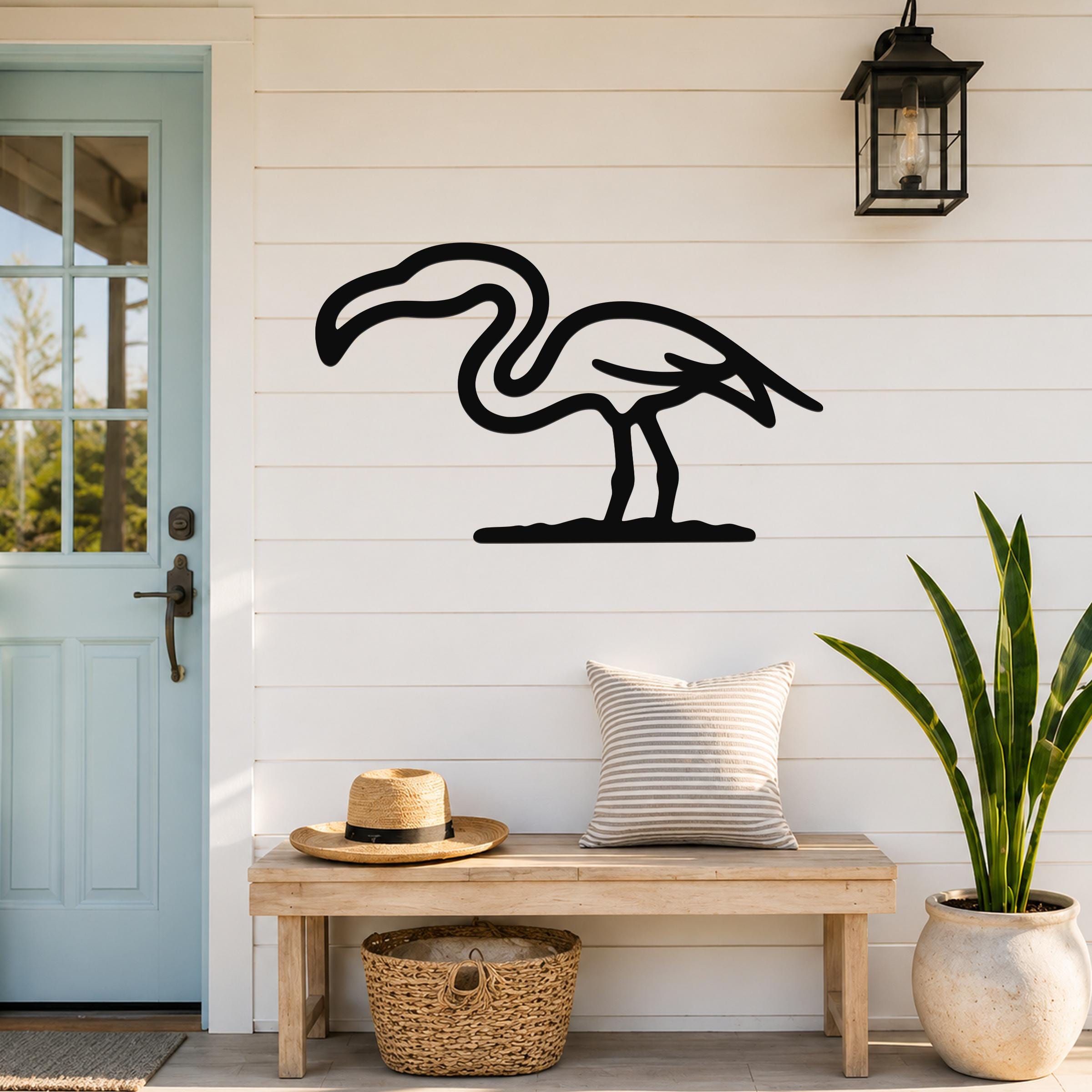 Black metal flamingo wall art silhouette mounted on a white shiplap wall above a wooden bench in a porch entryway.