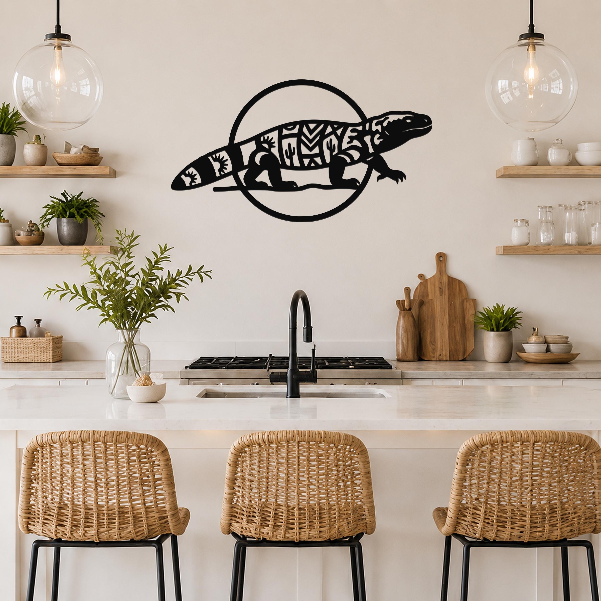 Black metal Gila monster wall art with intricate geometric and cactus cutouts, mounted on a kitchen wall above a counter.