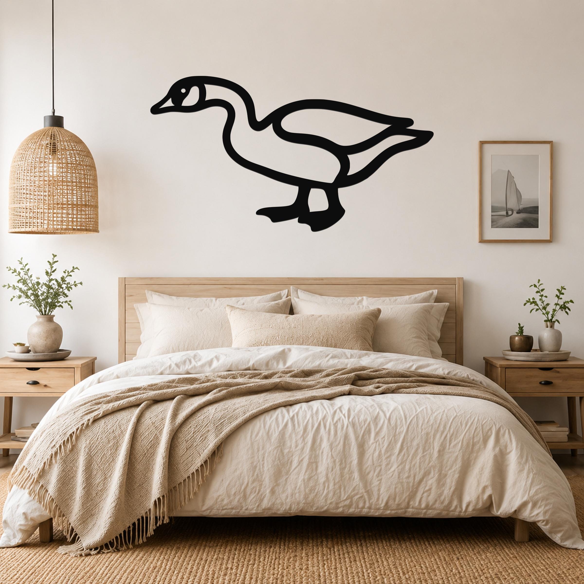 Black metal goose wall art silhouette mounted above a bed in a neutral bedroom.