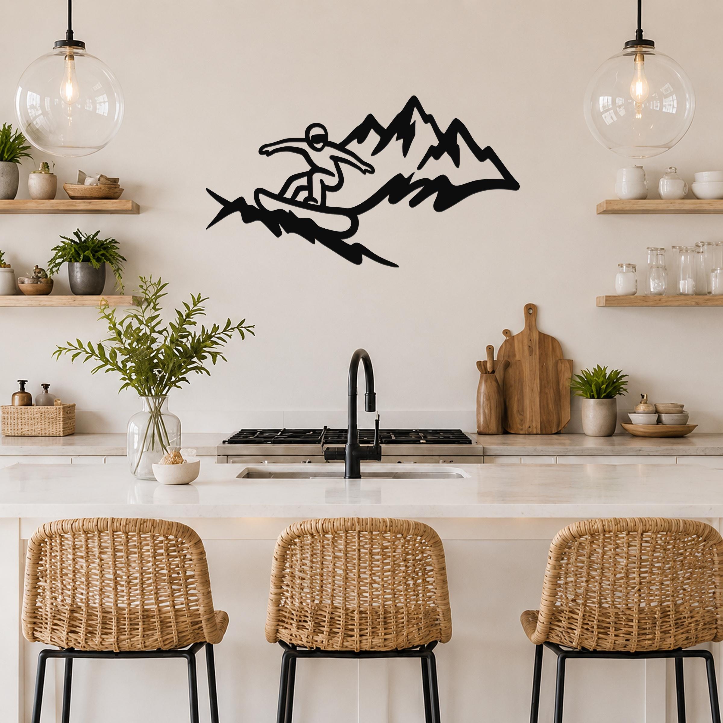 Black metal wall art featuring a snowboarder silhouette in motion against mountain peaks, mounted above a kitchen counter.