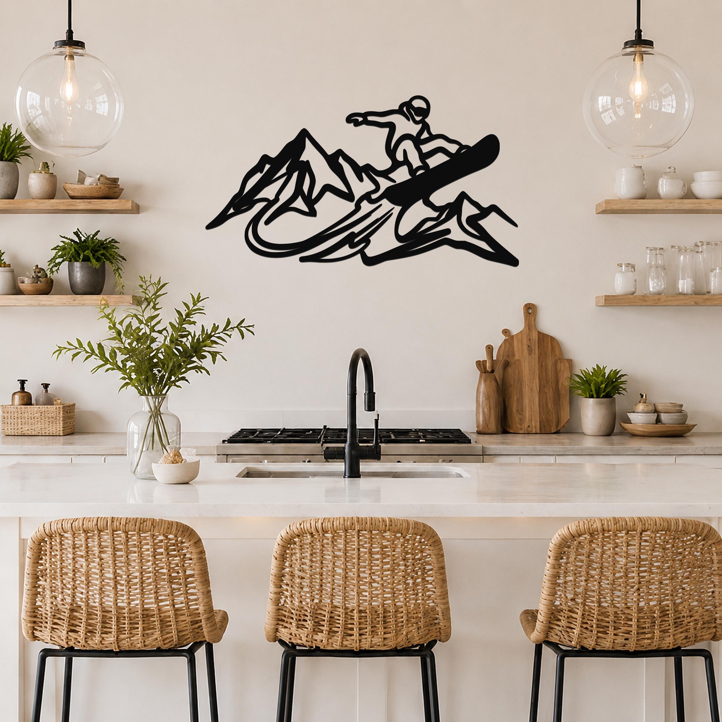 Black metal wall art featuring a snowboarder silhouette above mountain peaks, mounted on a kitchen wall above a counter.