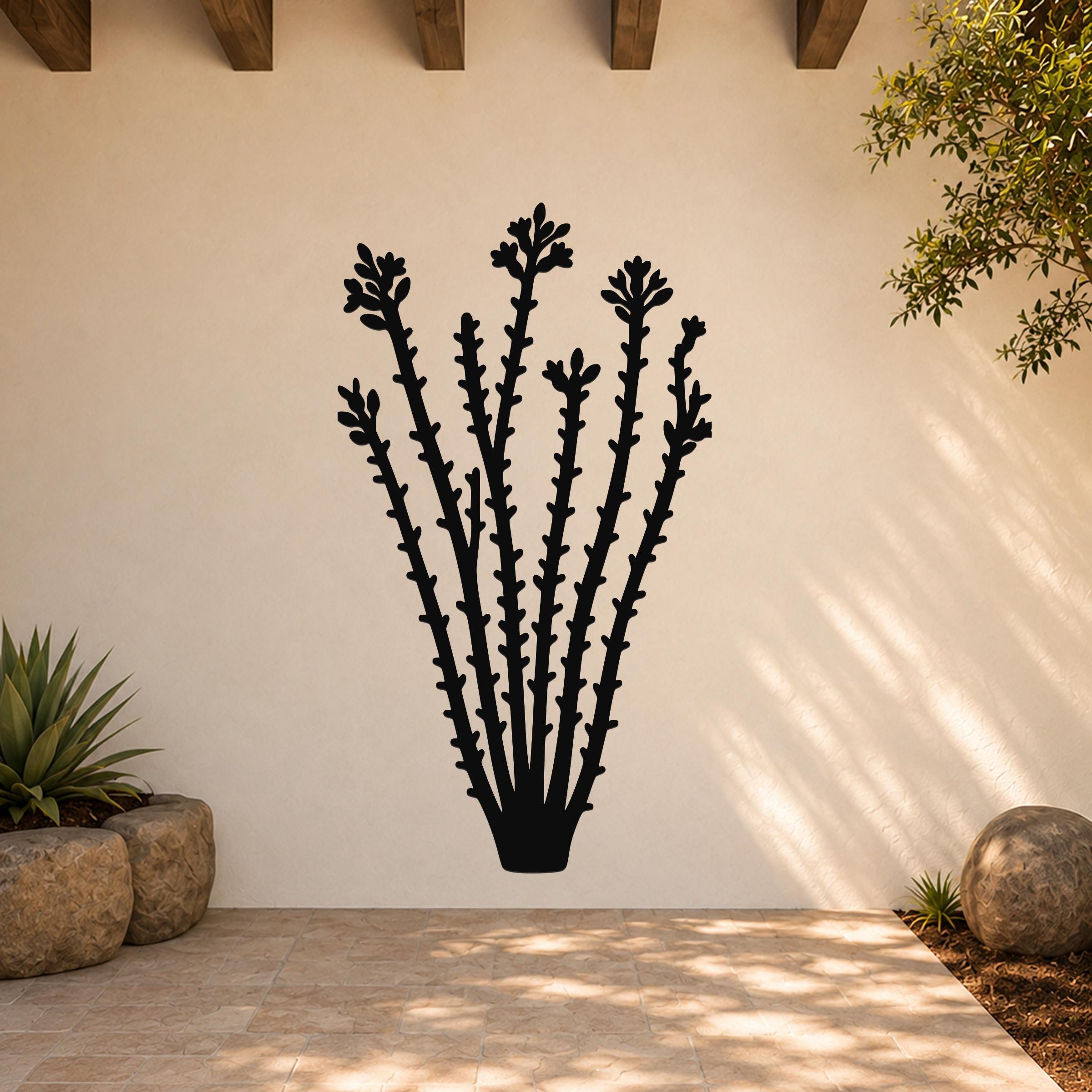 Black metal ocotillo wall art with flower and branch cutouts, mounted on a beige outdoor wall above a tiled patio.