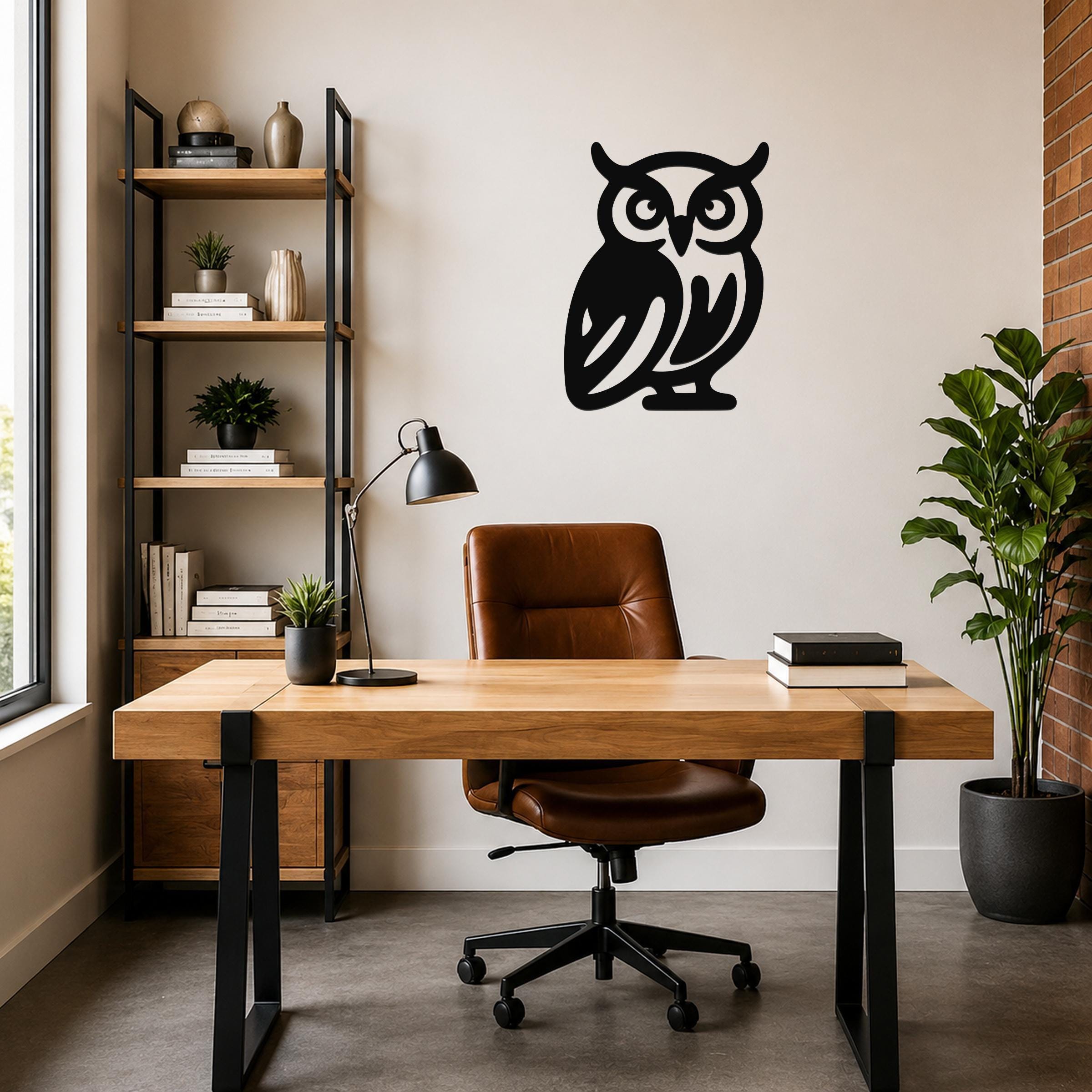 Black metal owl wall art with cutout details, mounted on a wall above a wooden desk in a home office.