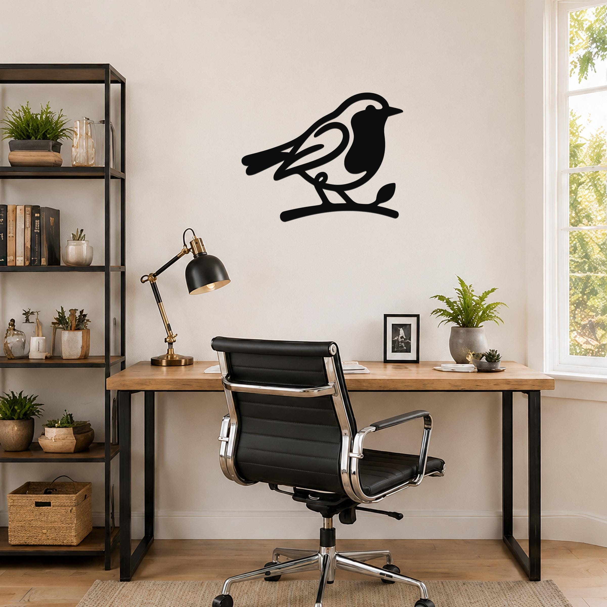 Black metal robin wall art silhouette perched on a branch, mounted on a wall above a wooden desk in a home office.