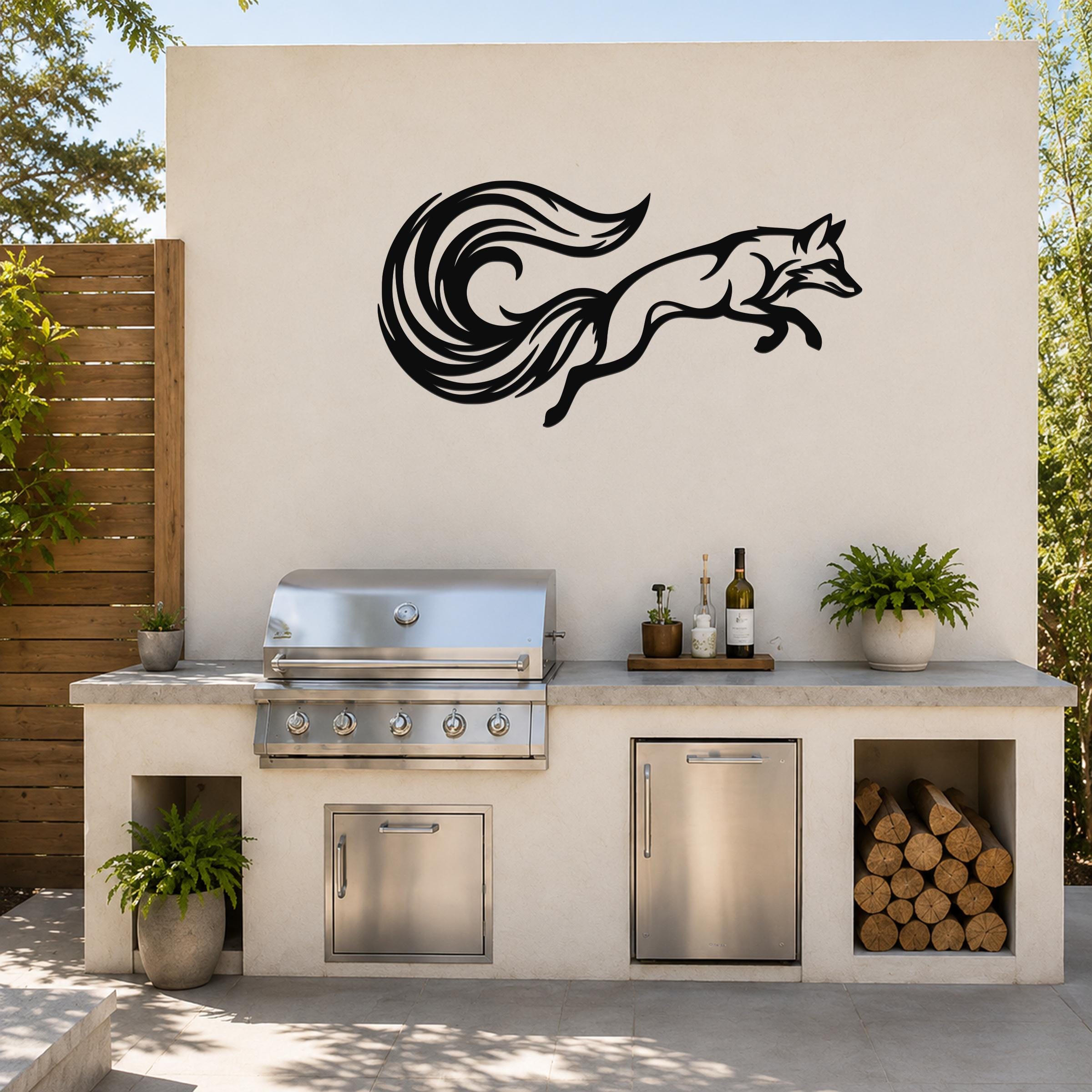 Black metal fox wall art with flowing tail cutout, mounted on an outdoor kitchen wall above a stainless steel grill.