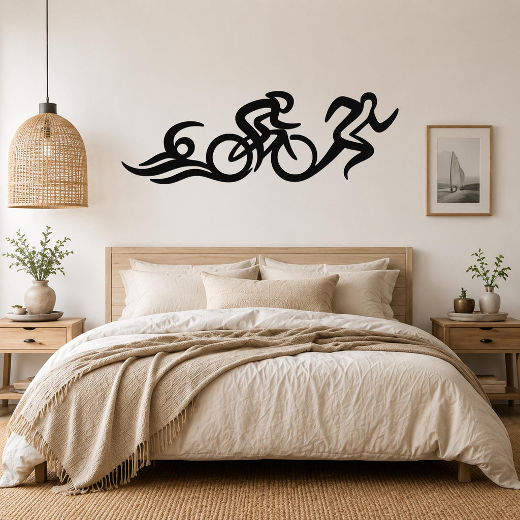 Black metal triathlon wall art with flowing swim, bike, and run silhouettes, mounted above a bed in a neutral bedroom.