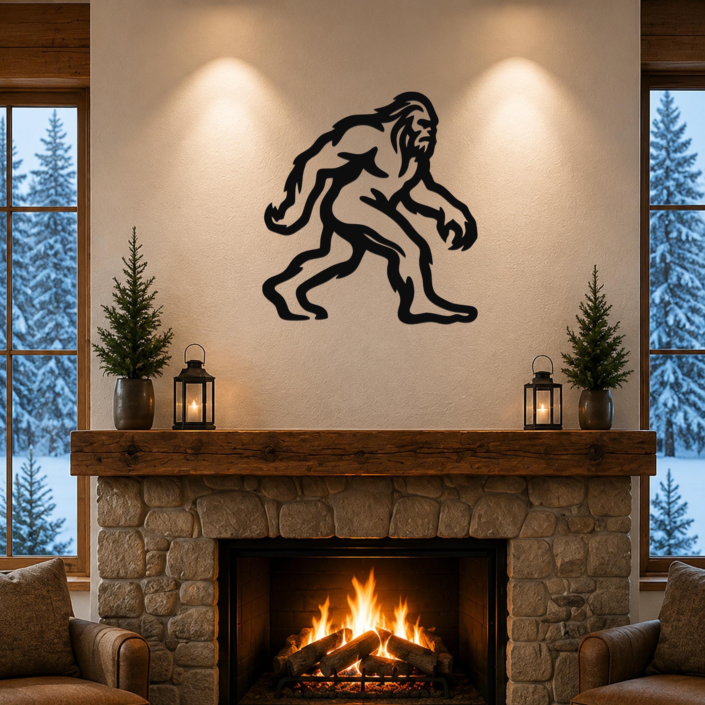 Black metal Bigfoot wall art silhouette with motion-line cutouts, mounted above a stone fireplace in a rustic living room.