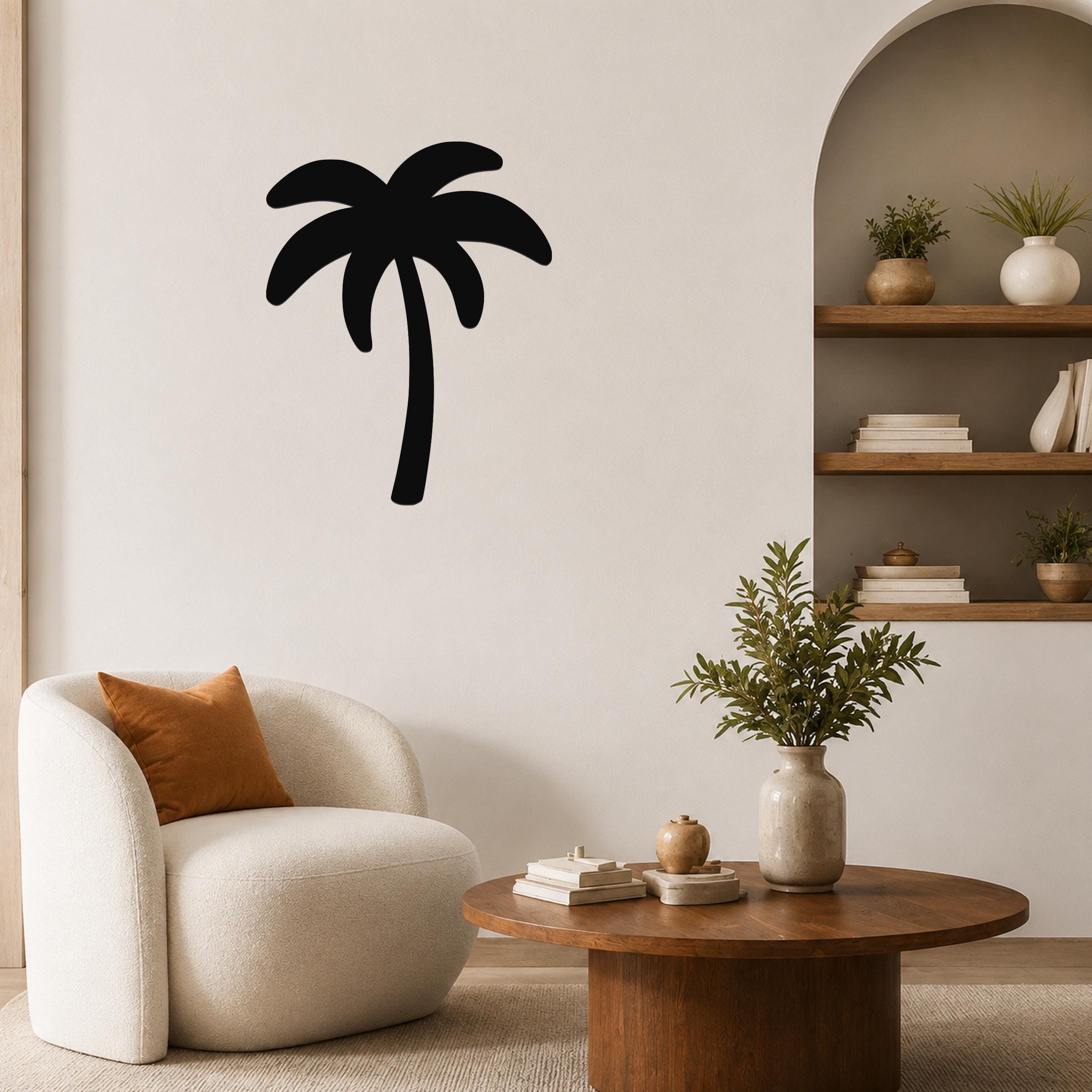 Black metal palm tree wall art silhouette mounted on a living room wall above a white armchair.