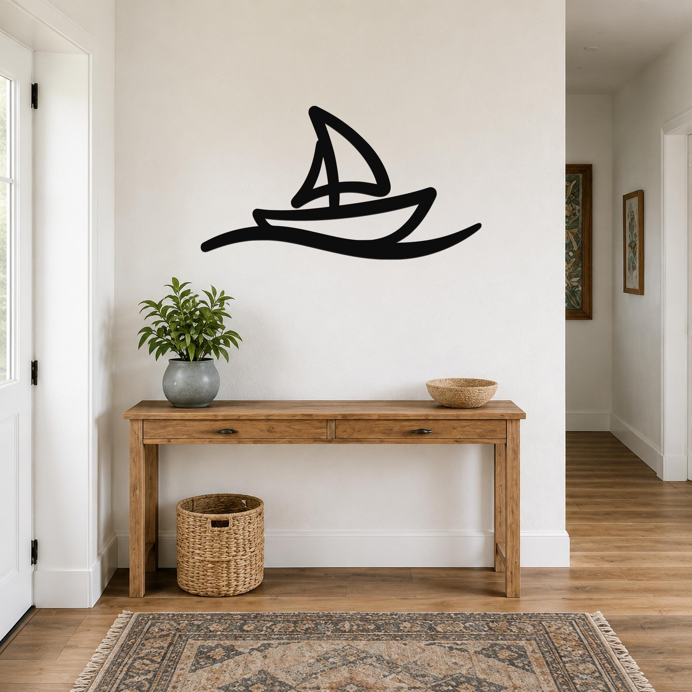 Black metal sailboat wall art with wave cutout, mounted above a wooden console table in a hallway.