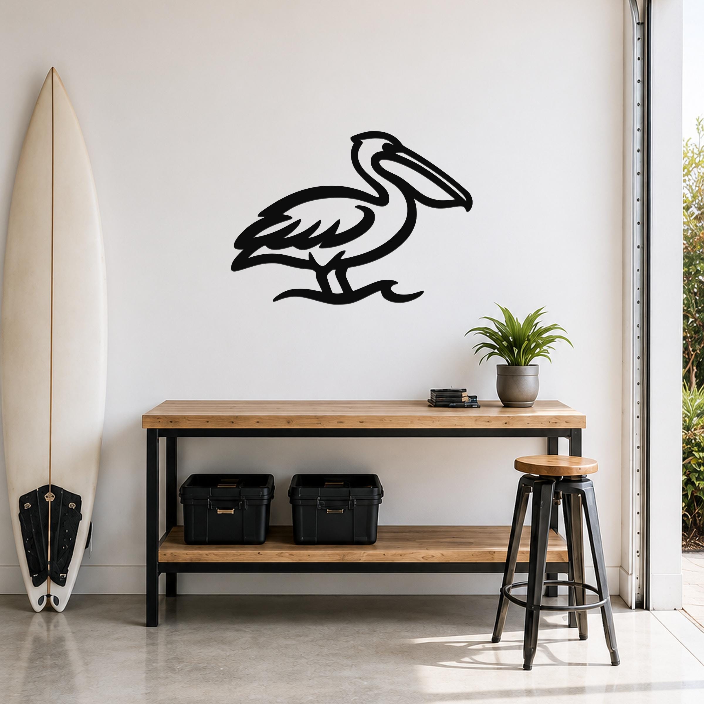 Black metal pelican wall art with a cutout silhouette, mounted on a white wall above a wooden counter in a coastal-style room.