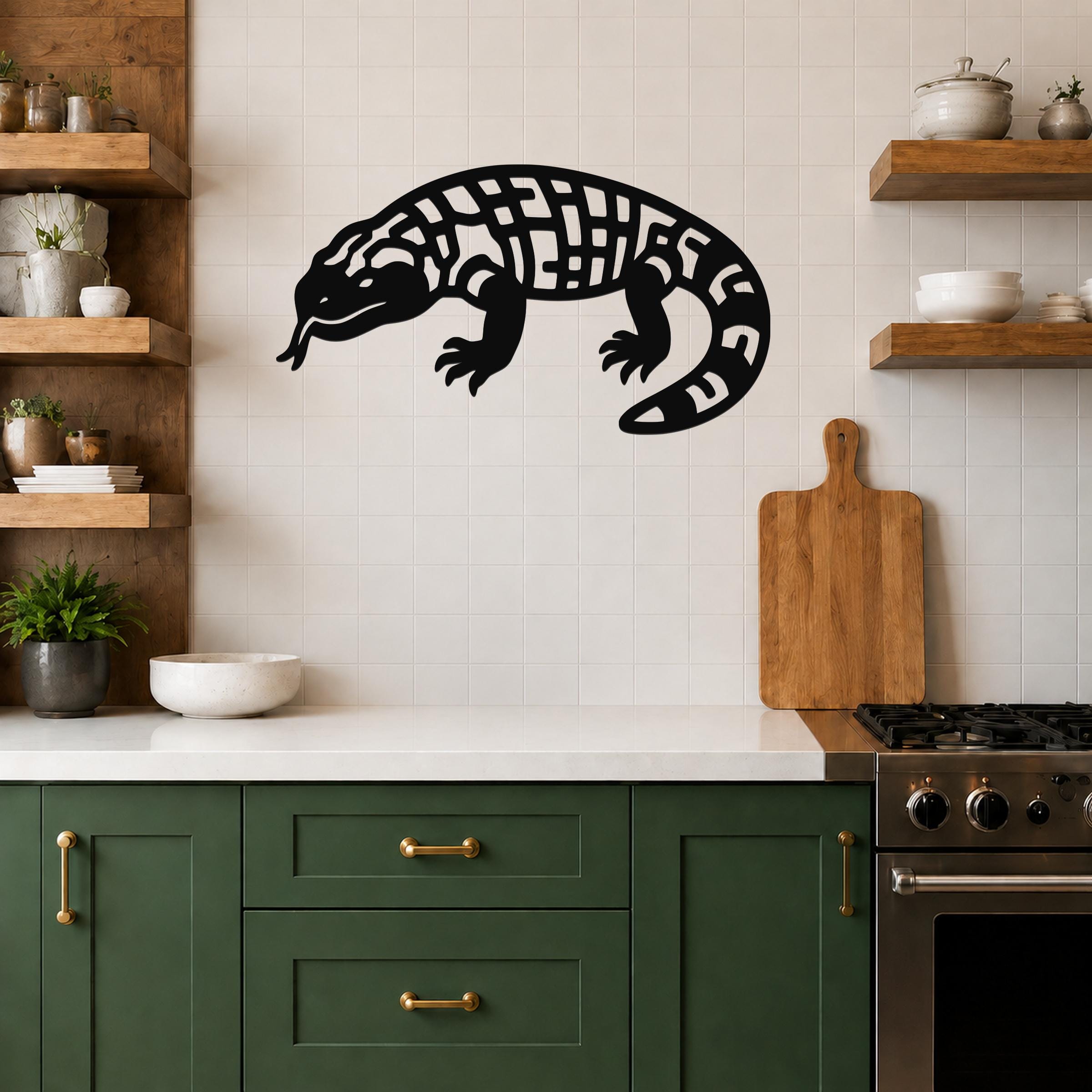 Black metal Gila monster wall art with intricate internal cutouts, mounted on a tiled kitchen wall above a counter.