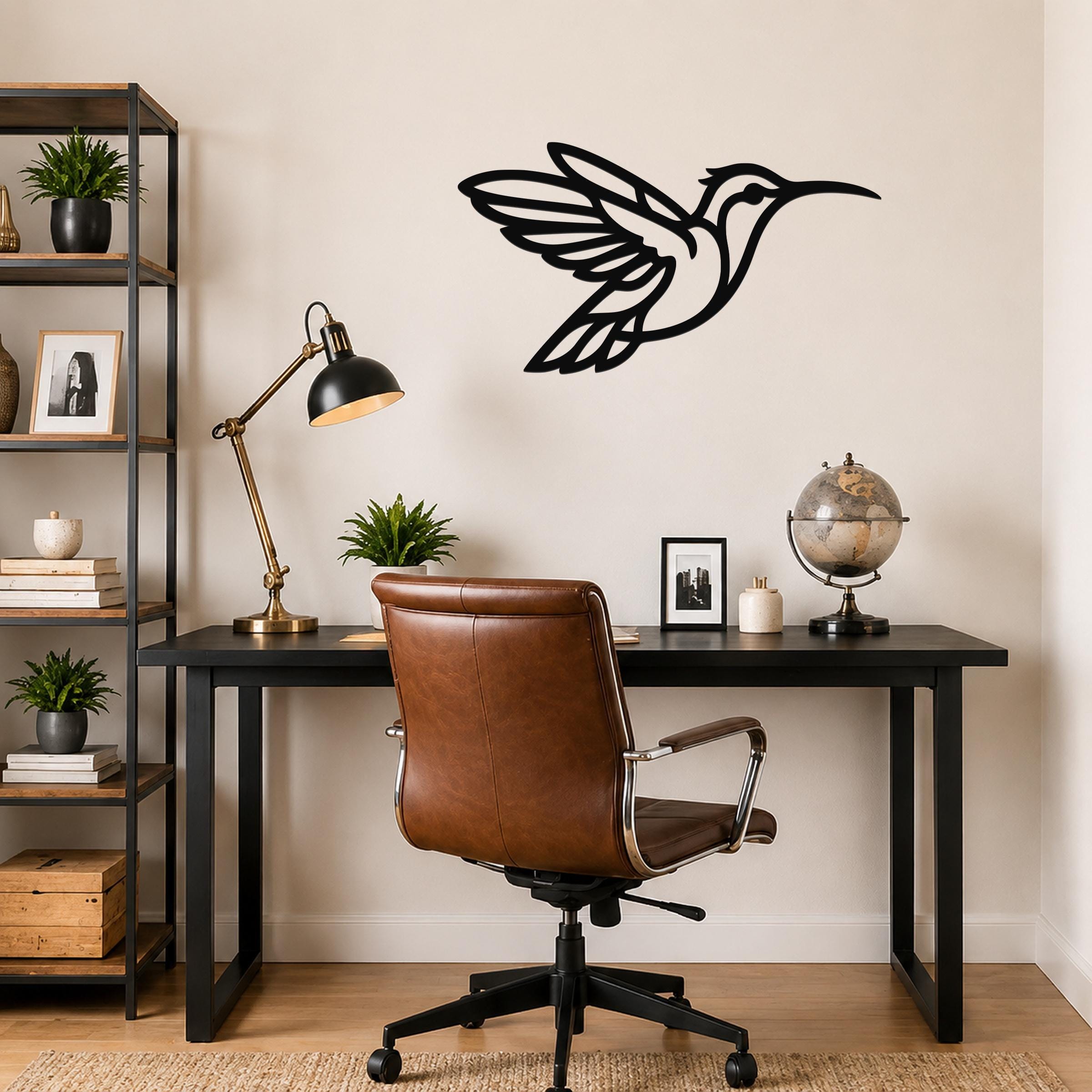 Black metal hummingbird wall art with motion-line cutouts, mounted above a black desk in a home office.