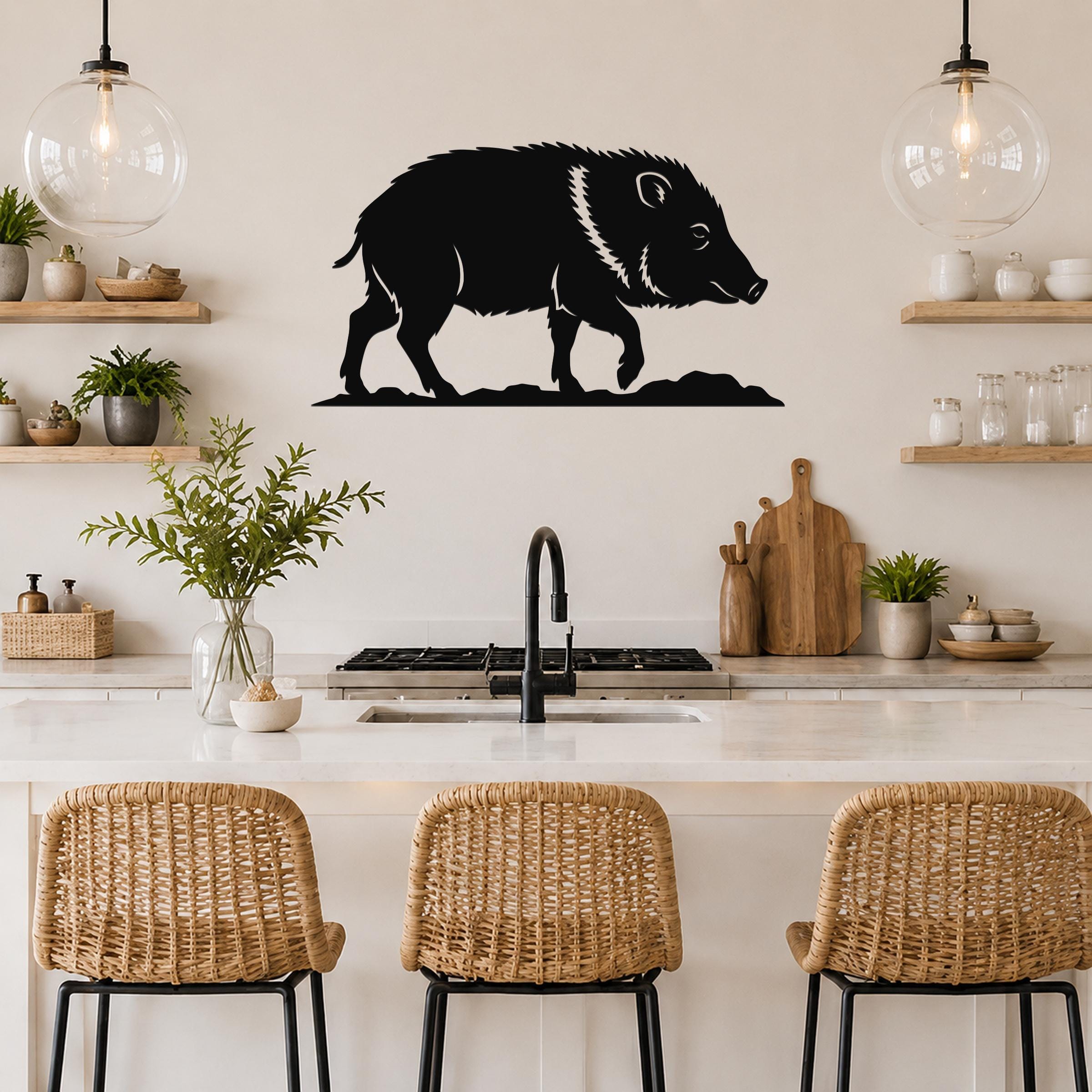 Black metal javelina wall art silhouette mounted above a kitchen counter, featuring a cutout design of a wild pig with a white stripe on its back.