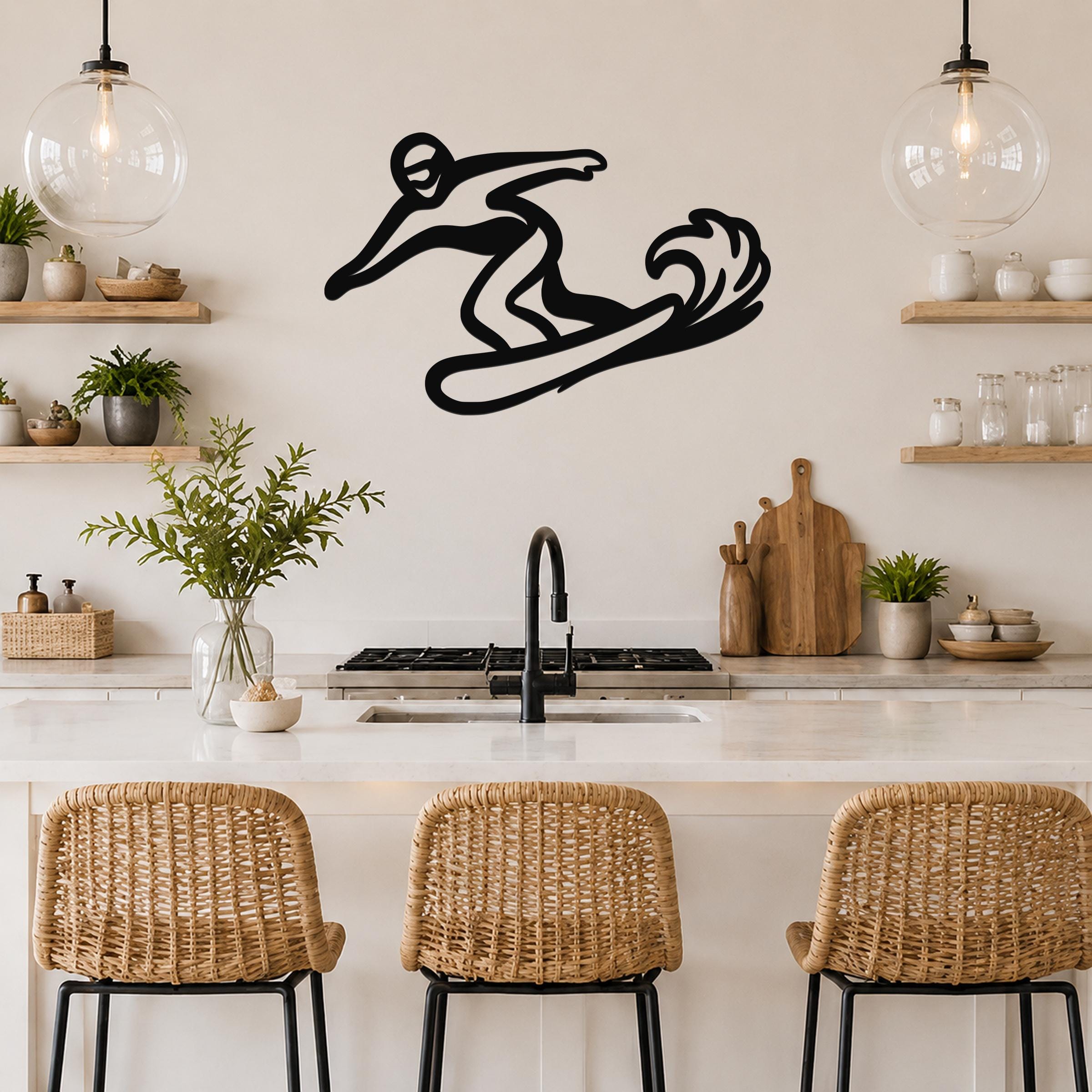 Black metal wall art silhouette of a snowboarder in motion, mounted on a kitchen wall above a counter with wicker bar stools.