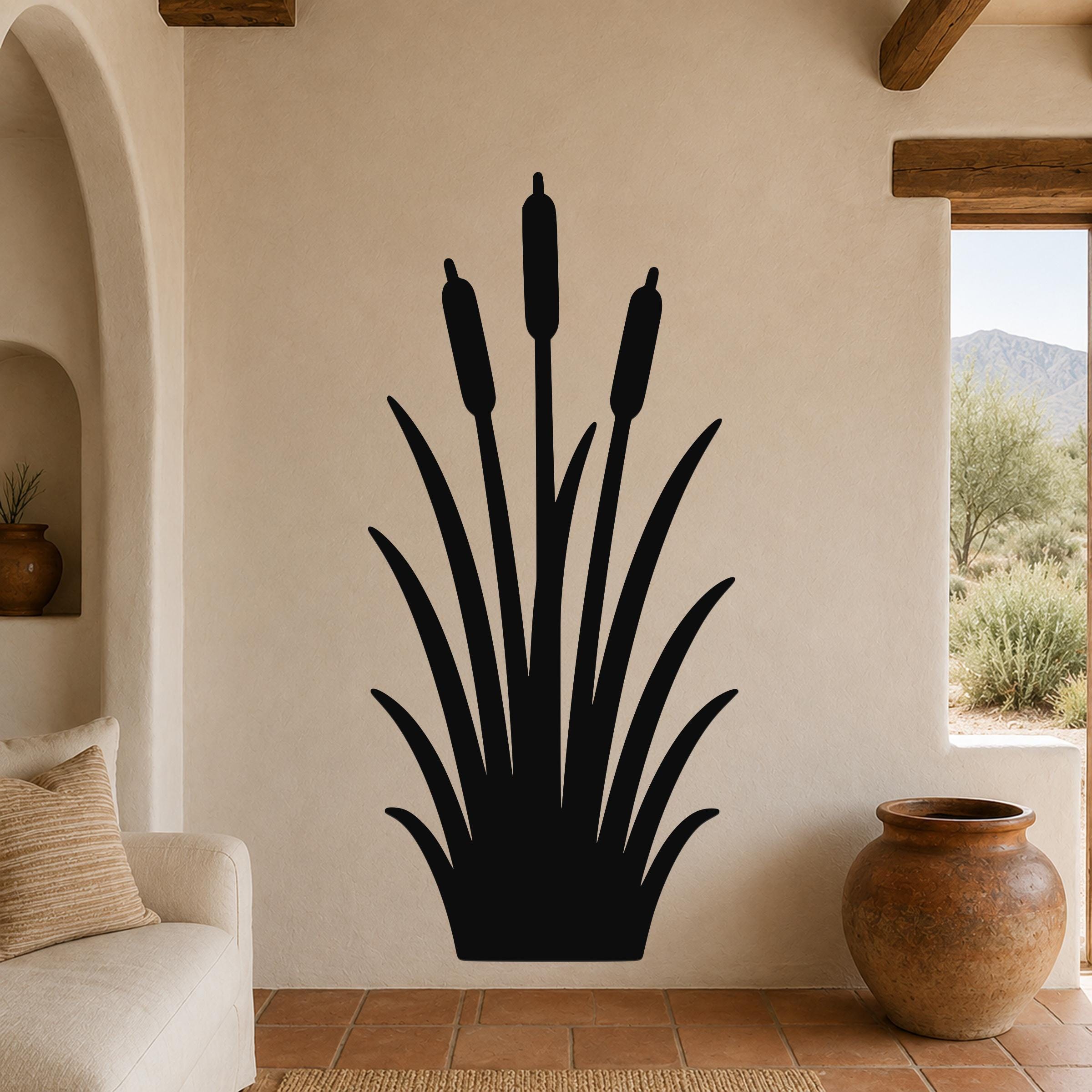 Black metal cattail wall art silhouette with tall stems and seed heads, mounted on a beige living room wall above a sofa.