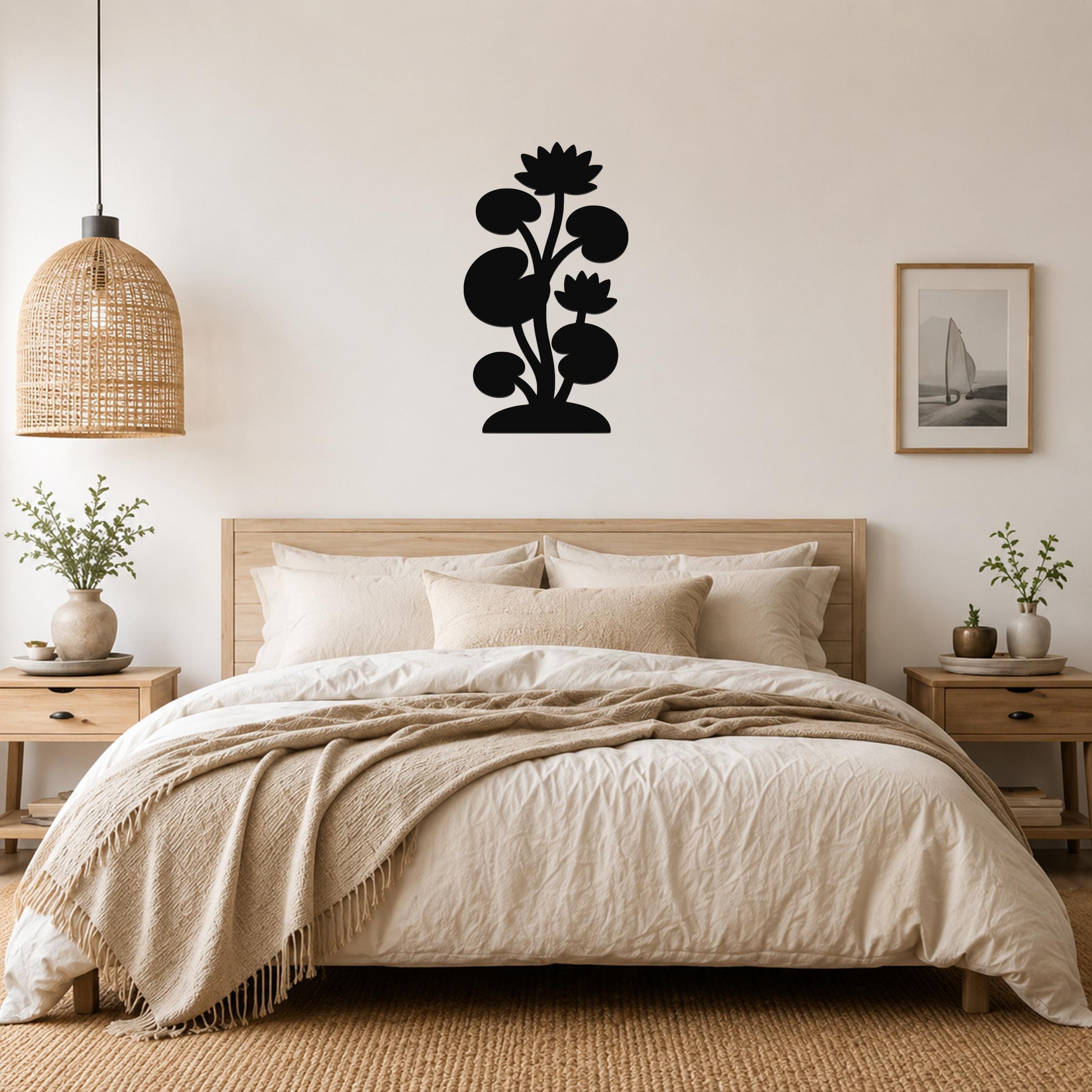 Black metal lotus water lily wall art with layered flower and leaf cutouts, mounted above a bed in a neutral bedroom.