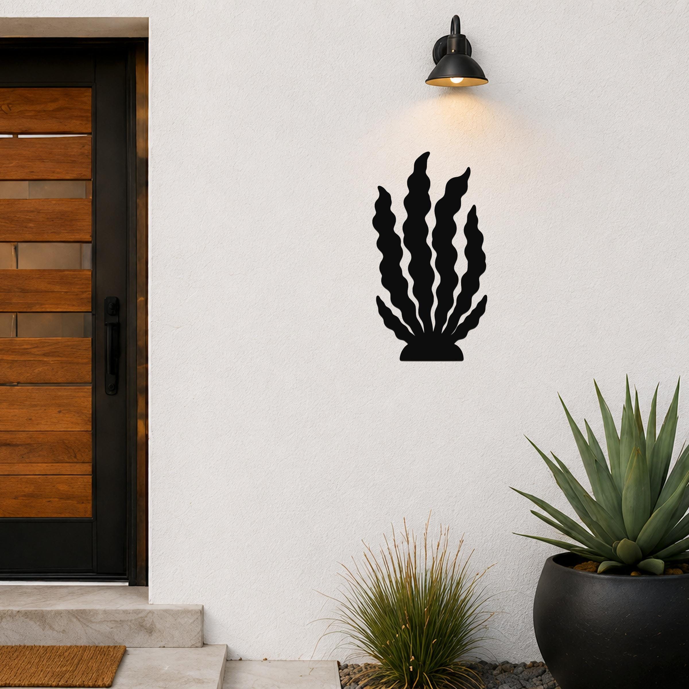 Black metal kelp wall art with wavy leaf cutouts, mounted on a white exterior wall above a potted succulent and near a front door.