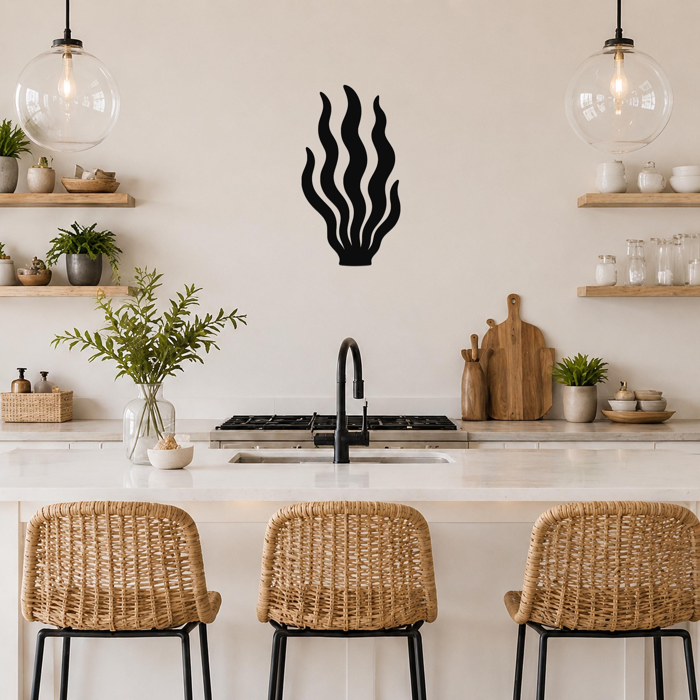 Black metal kelp wall art with flowing frond cutouts, mounted on a kitchen wall above a counter.