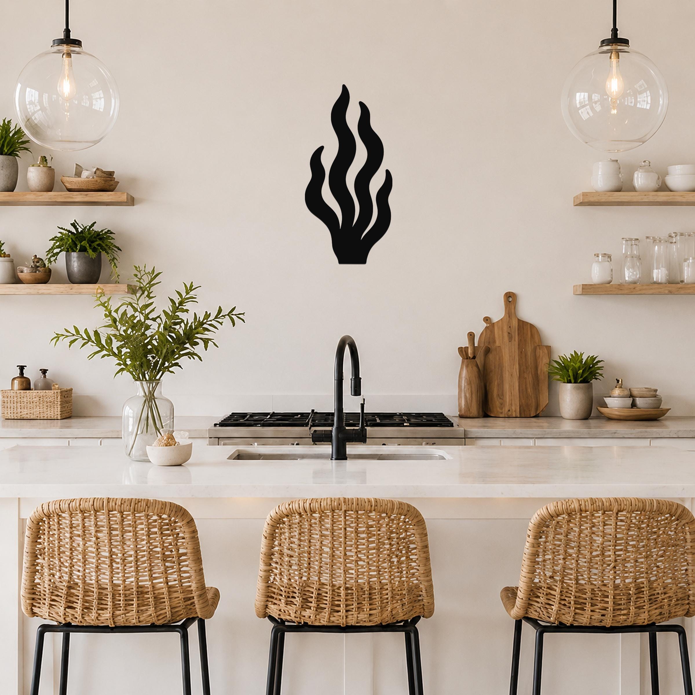 Black metal kelp wall art with flowing seaweed cutouts, mounted on a kitchen wall above a counter.