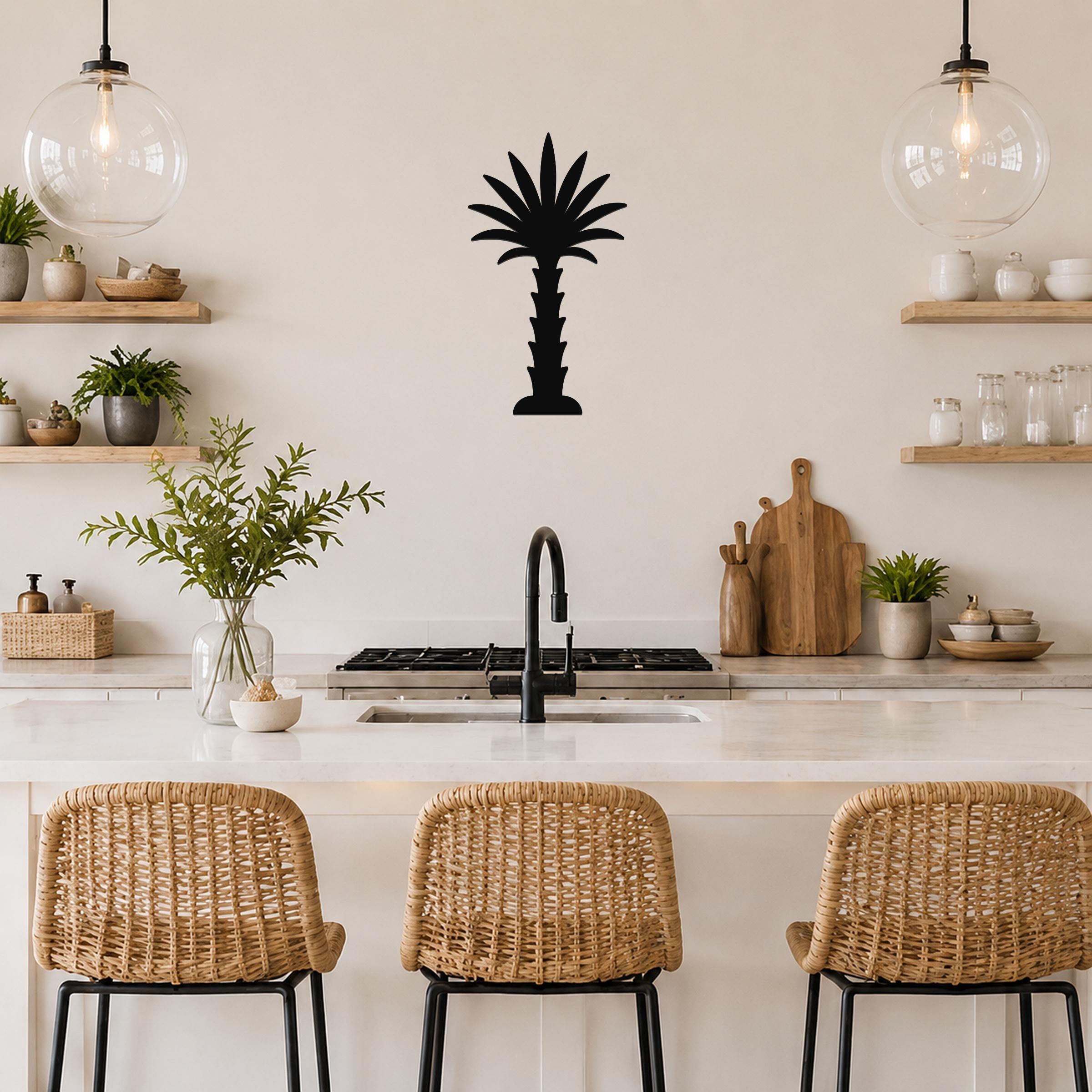 Black metal palm tree wall art silhouette mounted on a kitchen wall above a counter, with wicker bar stools and open shelving visible below.