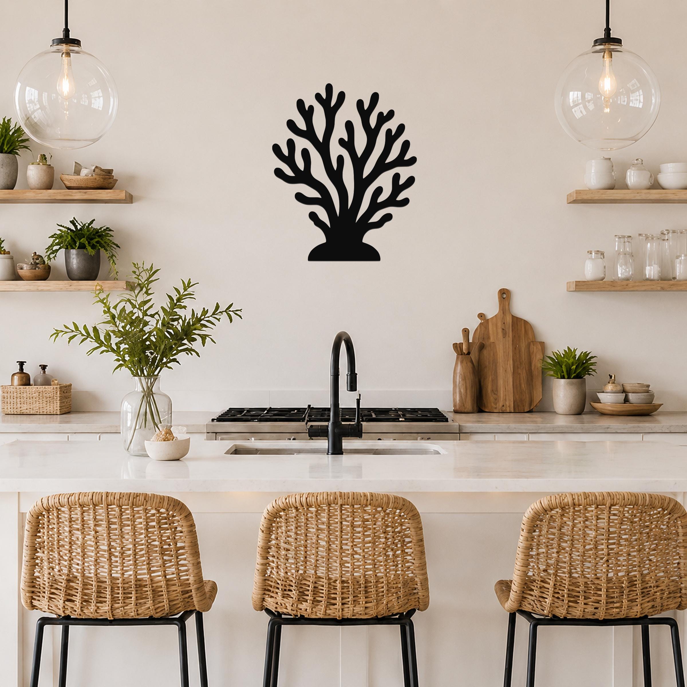 Black metal coral wall art with branching cutouts, mounted on a kitchen wall above a counter between two glass pendant lights.