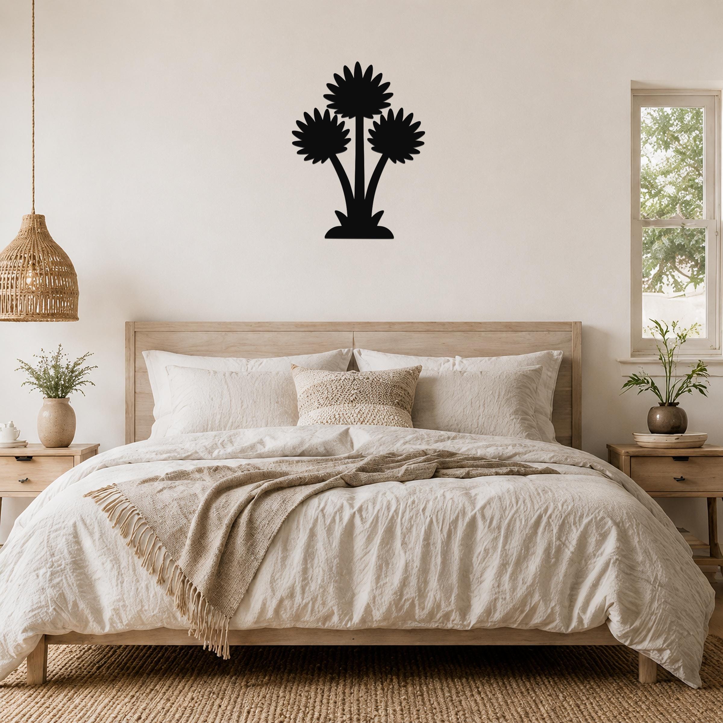Black metal wall art with a three-flower silhouette design, mounted above a wooden bed in a neutral bedroom.