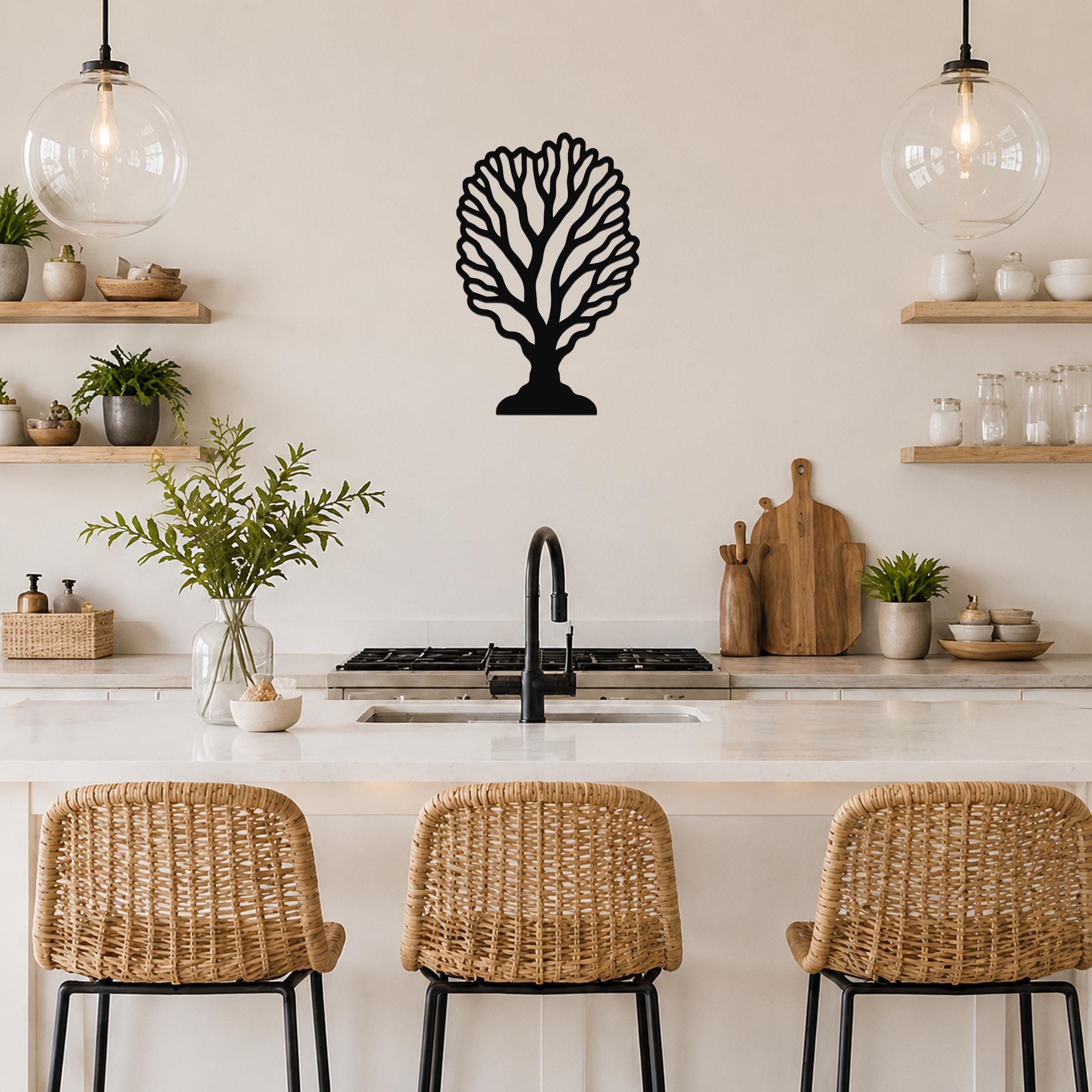Black metal fan coral wall art with intricate branch cutouts, mounted on a kitchen wall above a counter.