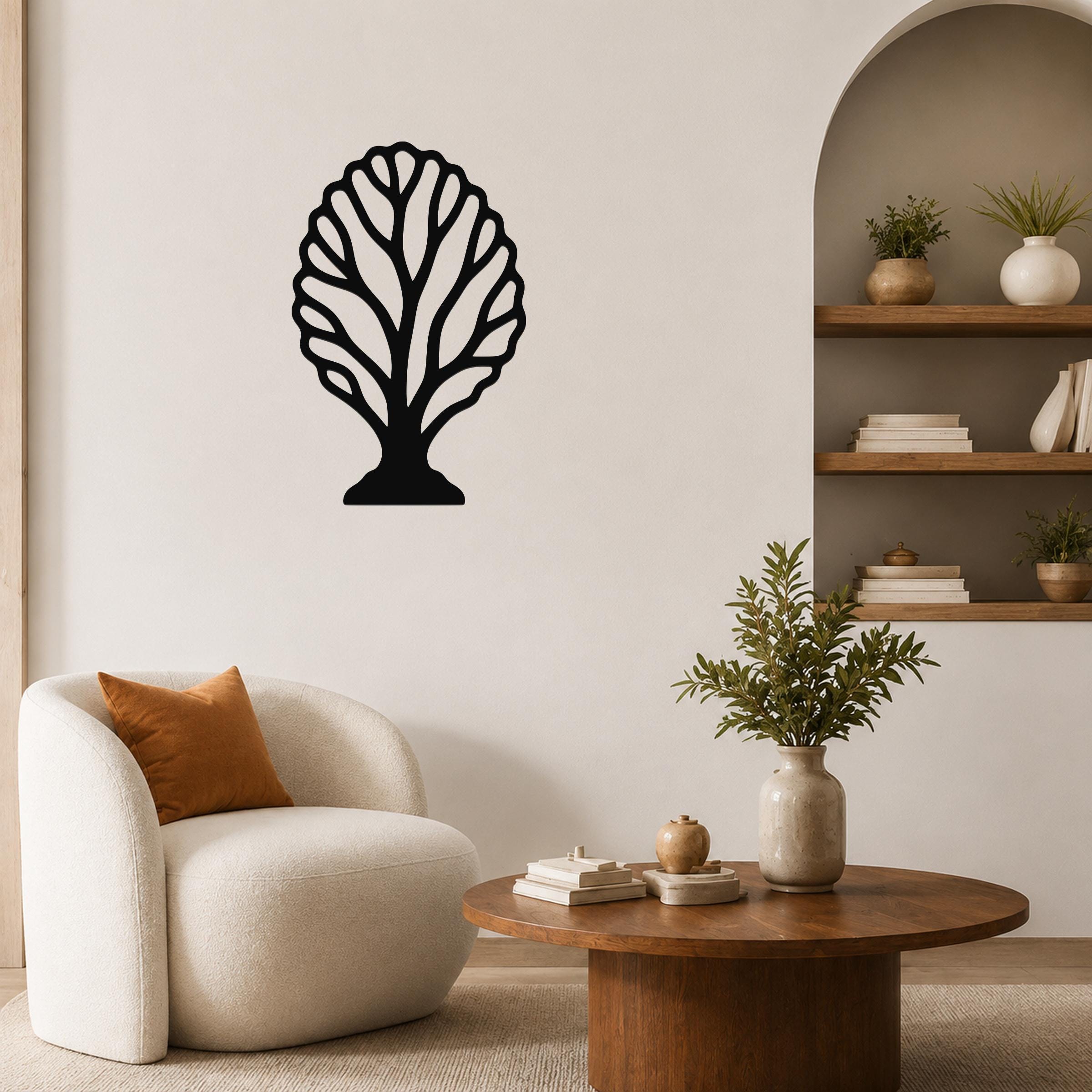 Black metal wall art in a fan coral silhouette, mounted on a living room wall above a white armchair.